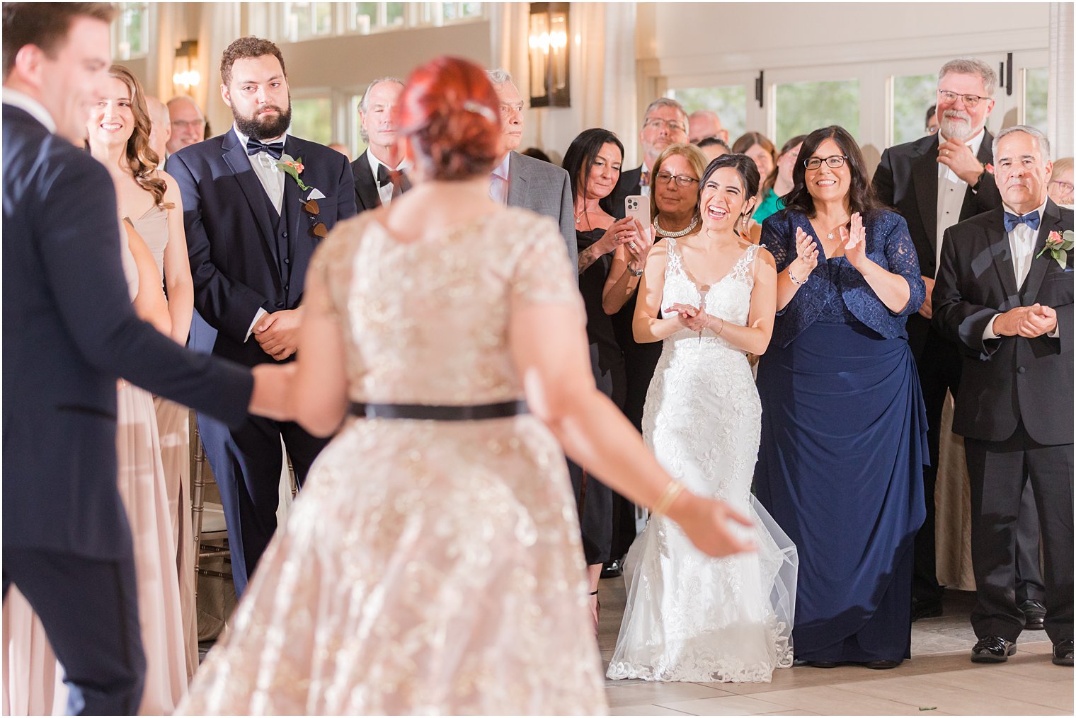 bride smiles at mother-in-law and husband on dance floor