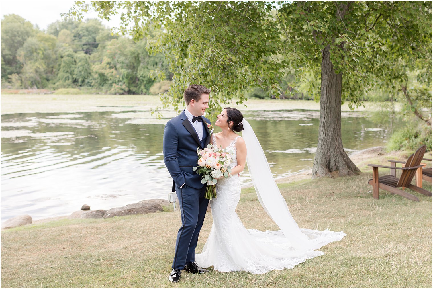 bride and groom smile at each other with bride's veil behind them