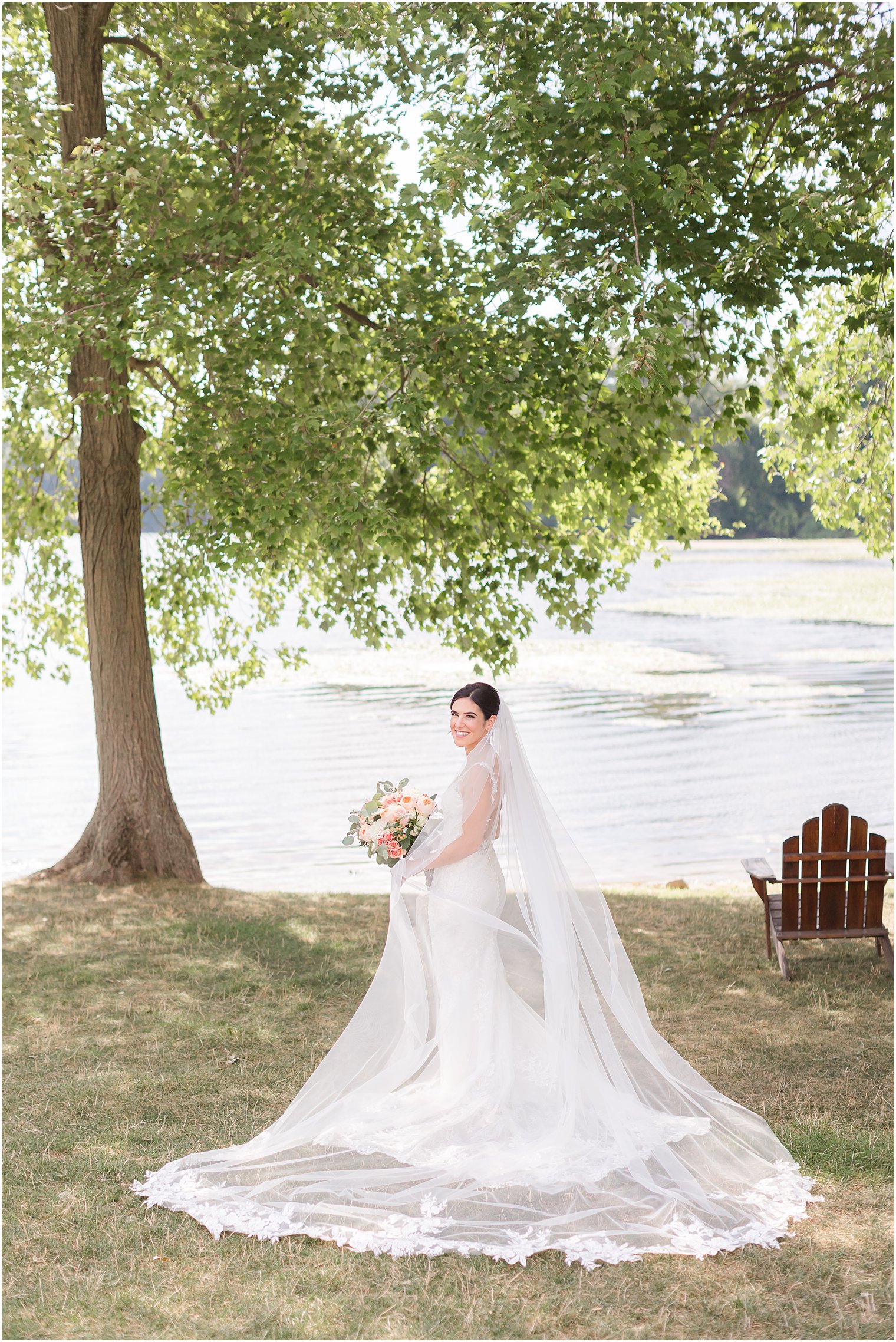 bride poses under trees with veil around her