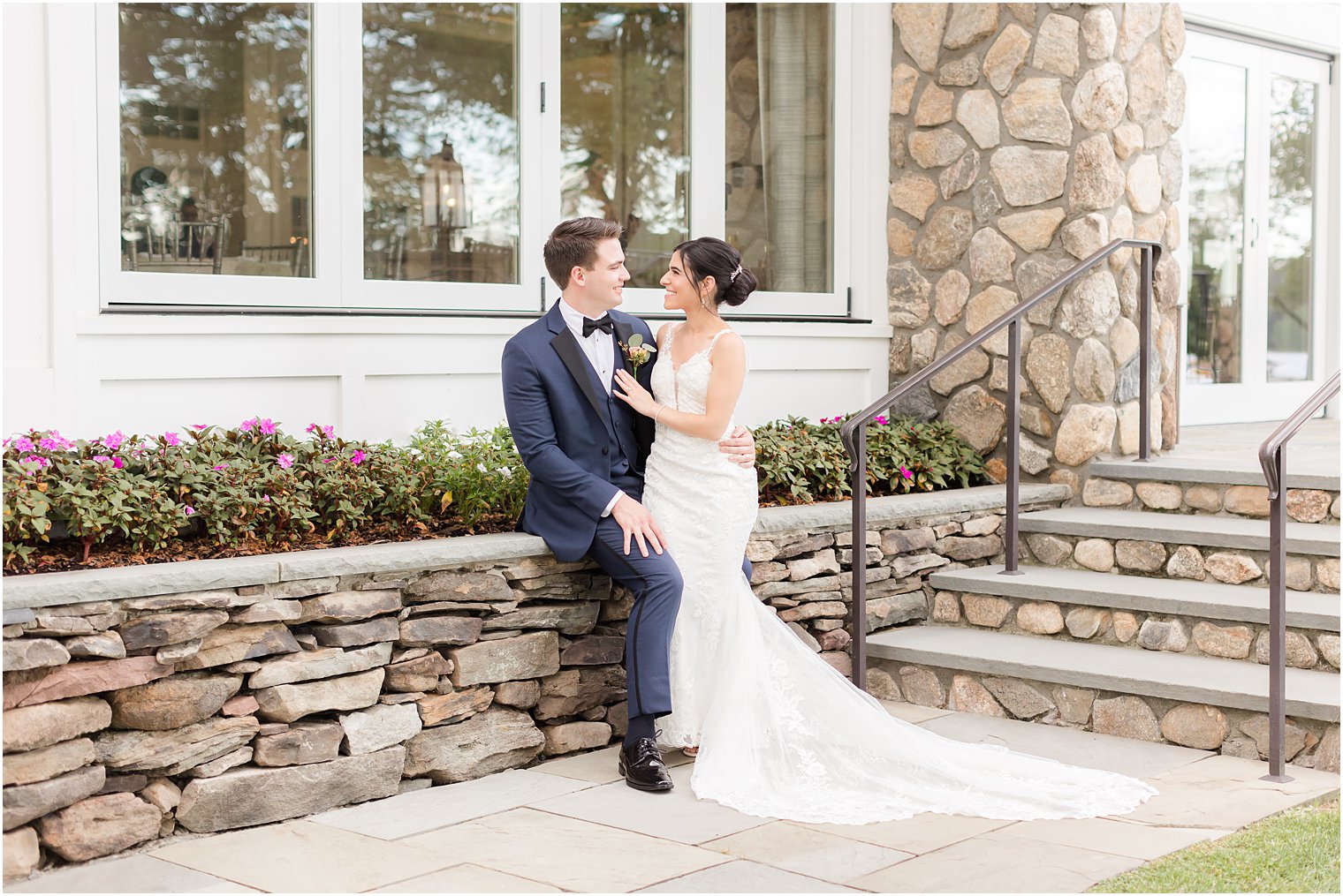 newlyweds lean against stone wall at Indian Trail Club