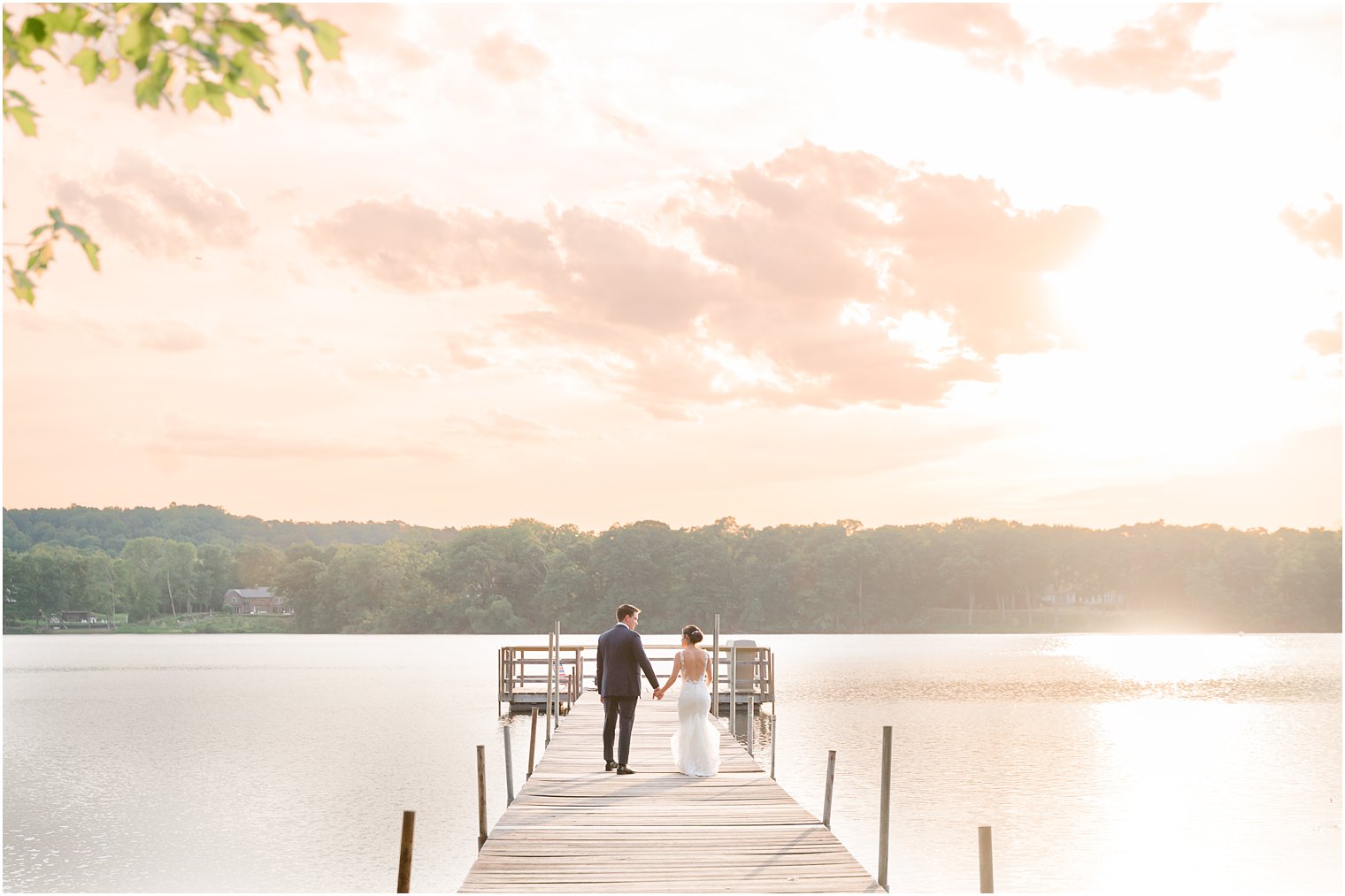 newlyweds hold hands walking on dock at Indian Trail Club