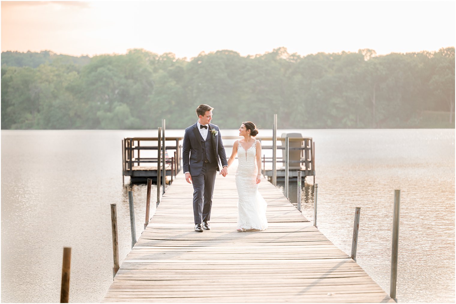 bride and groom walk on dock at Indian Trail Club during sunset