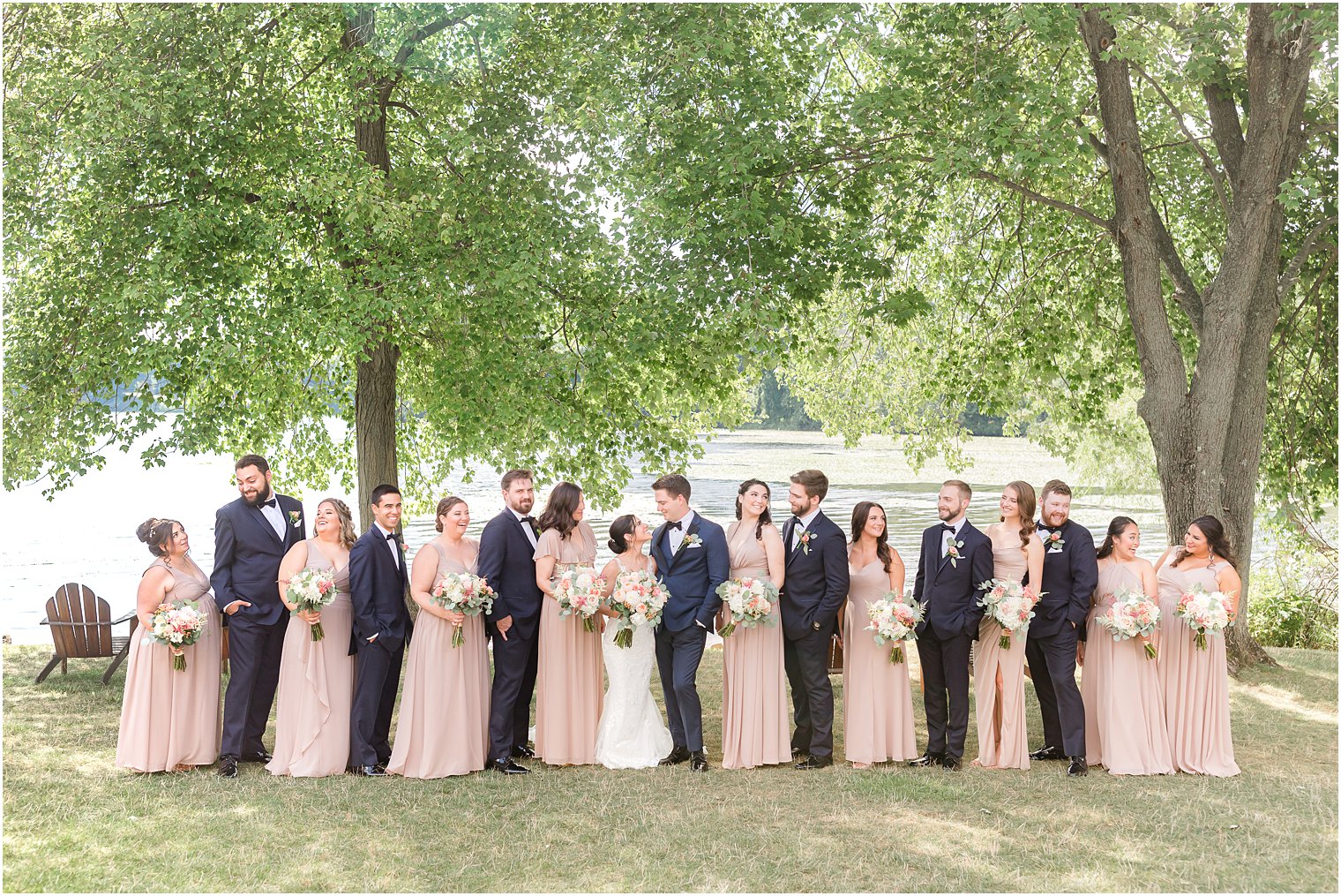 wedding party smiles with bride and groom along lake at Indian Trail Club