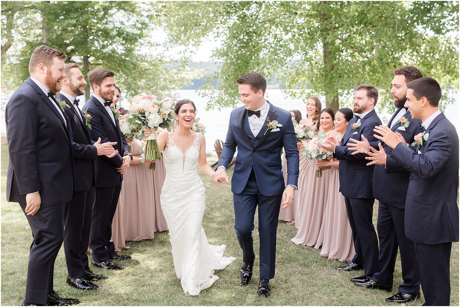 newlyweds hold hands walking through wedding party
