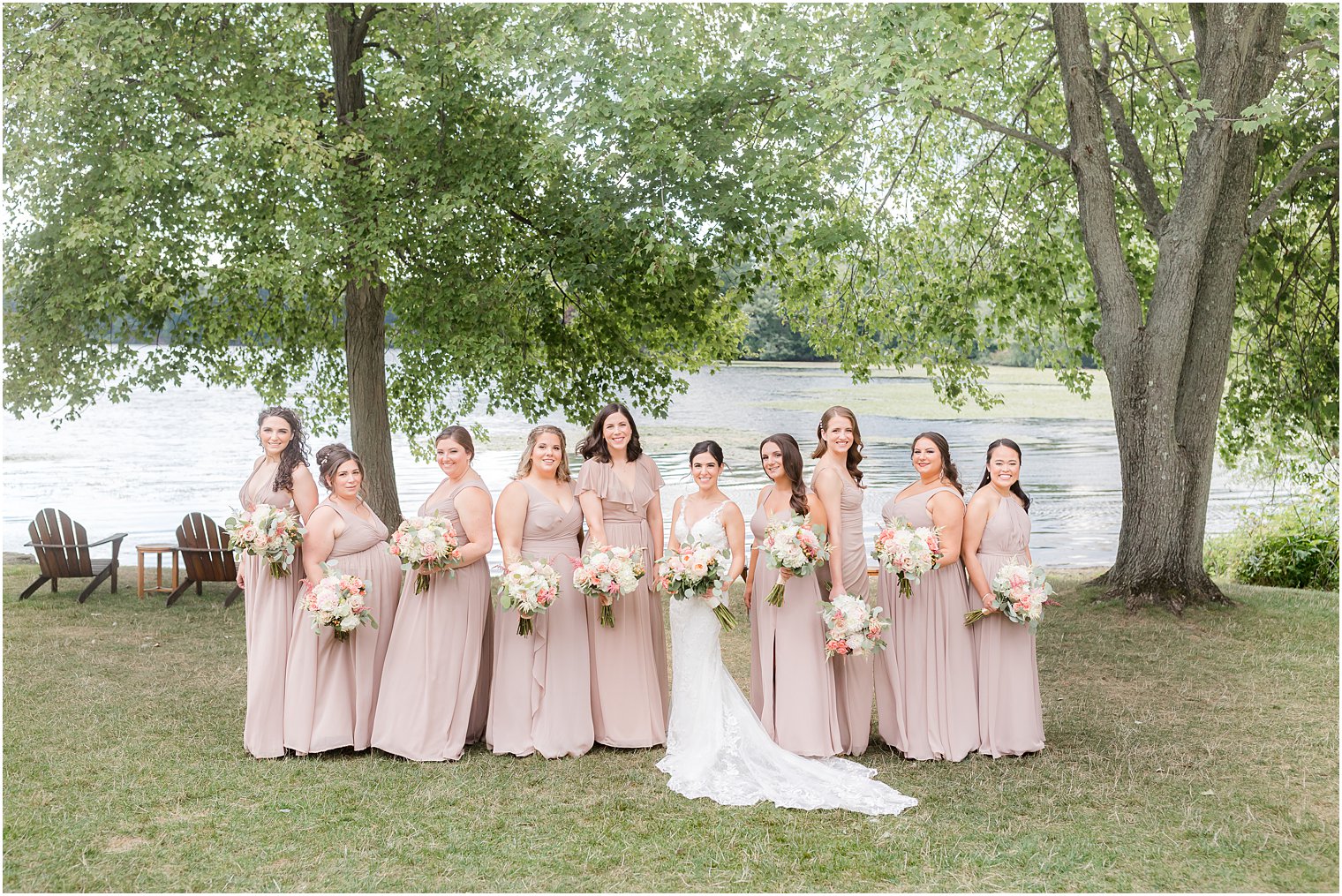 bride stands with bridesmaids in pale pink gowns