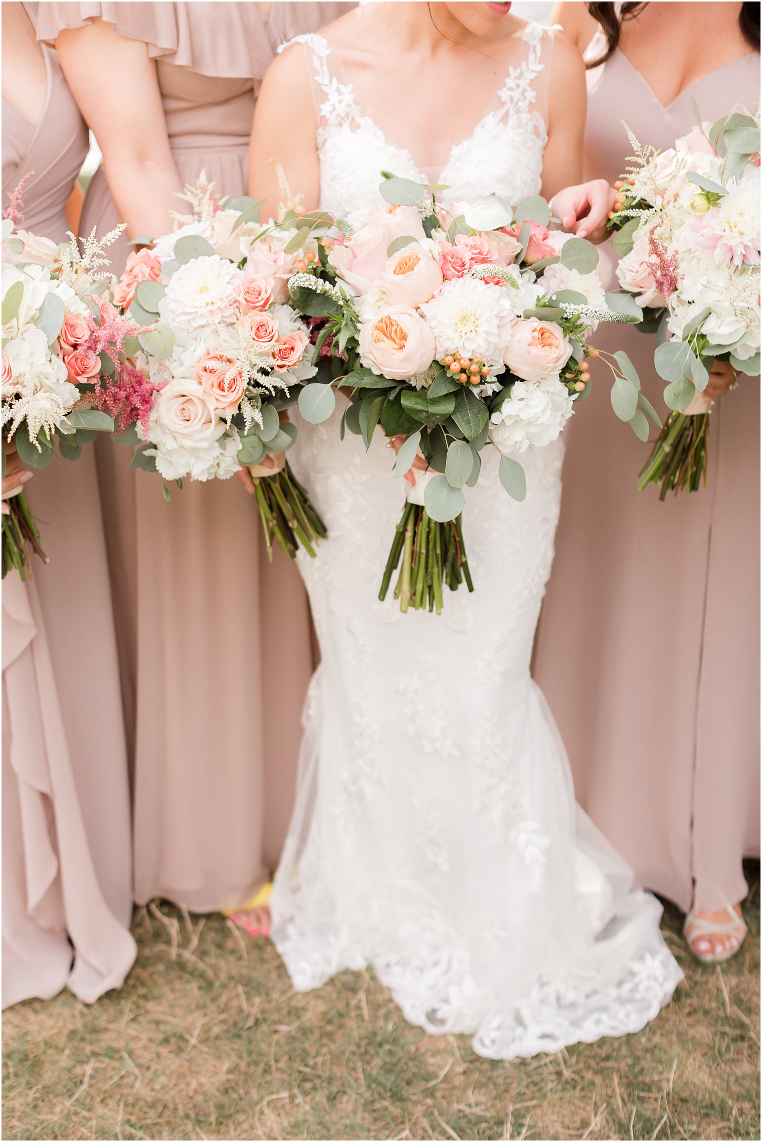 bride and bridesmaids hold bouquets of pink and white peonies