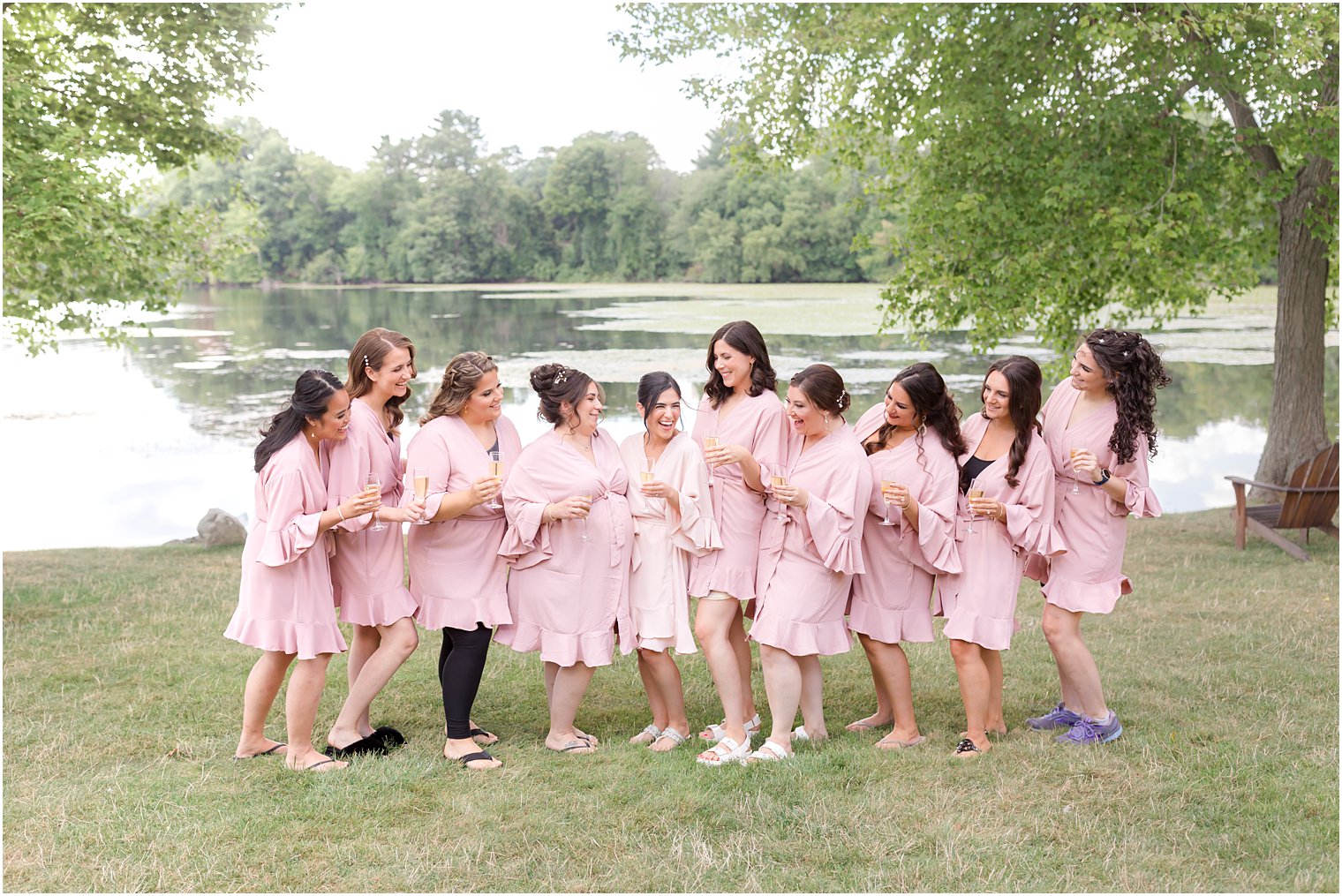 bride poses with bridesmaids in pink robes at Indian Trail Club