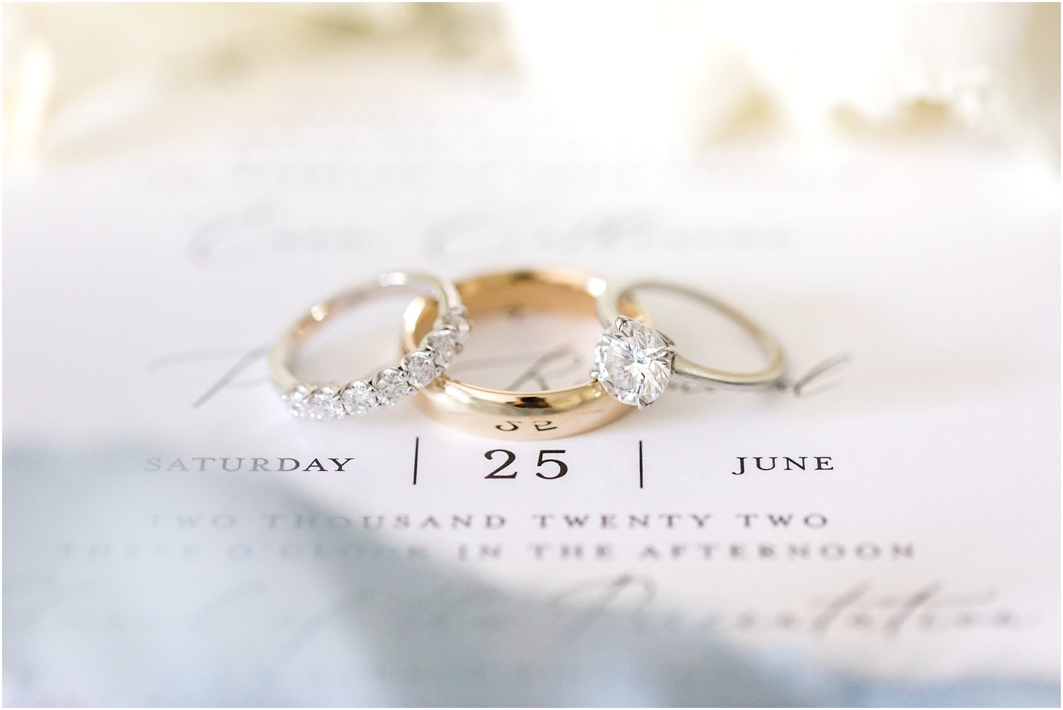 gold wedding bands rest on invitation suite 