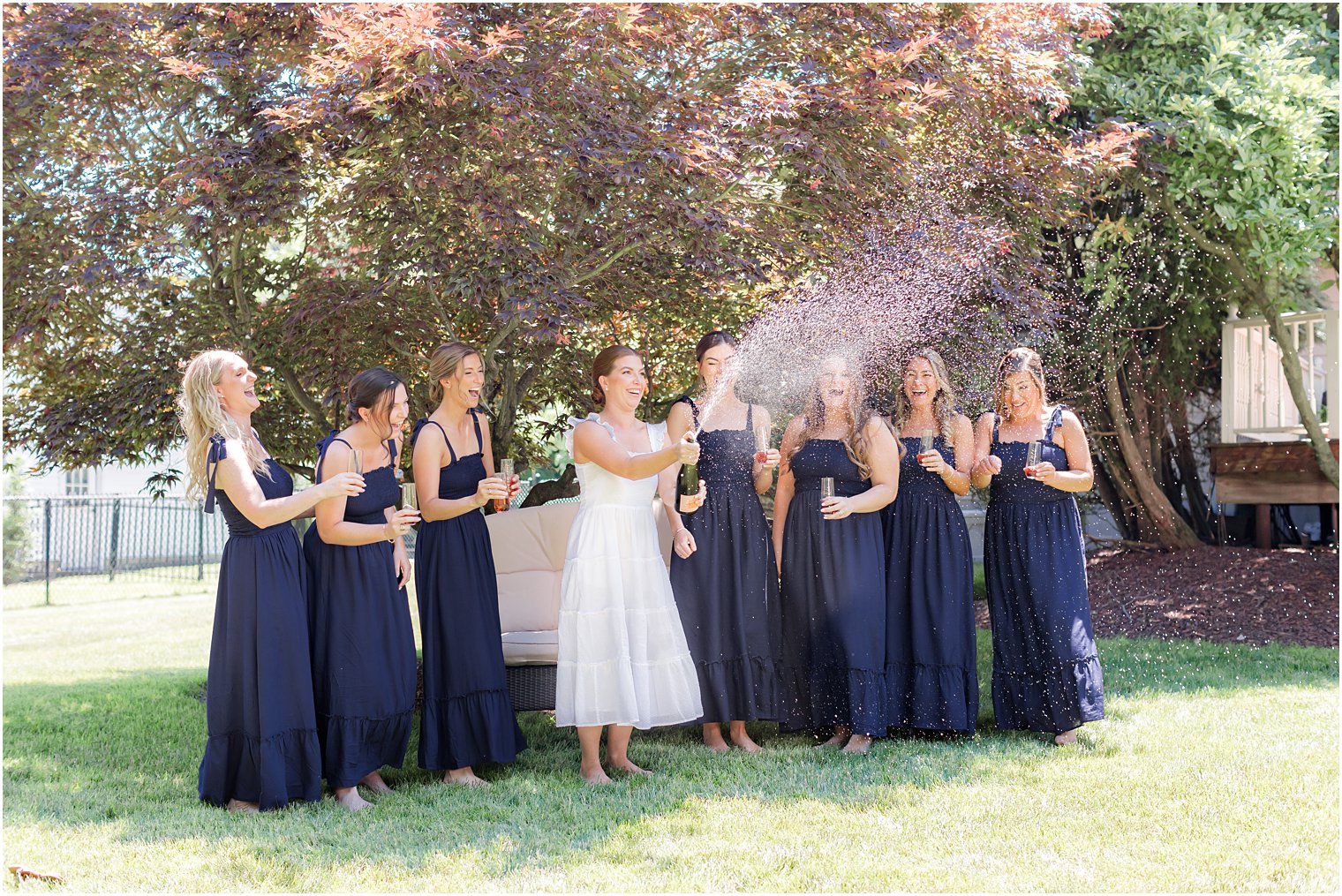 bride pops champagne with bridesmaids before summer Indian Trail Club wedding 