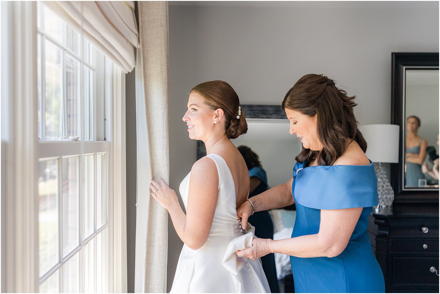 mother helps bride into wedding gown