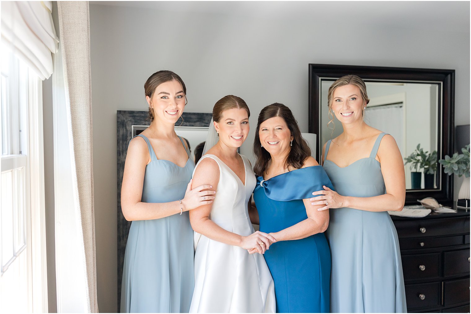 mother and bridesmaids pose with bride in home