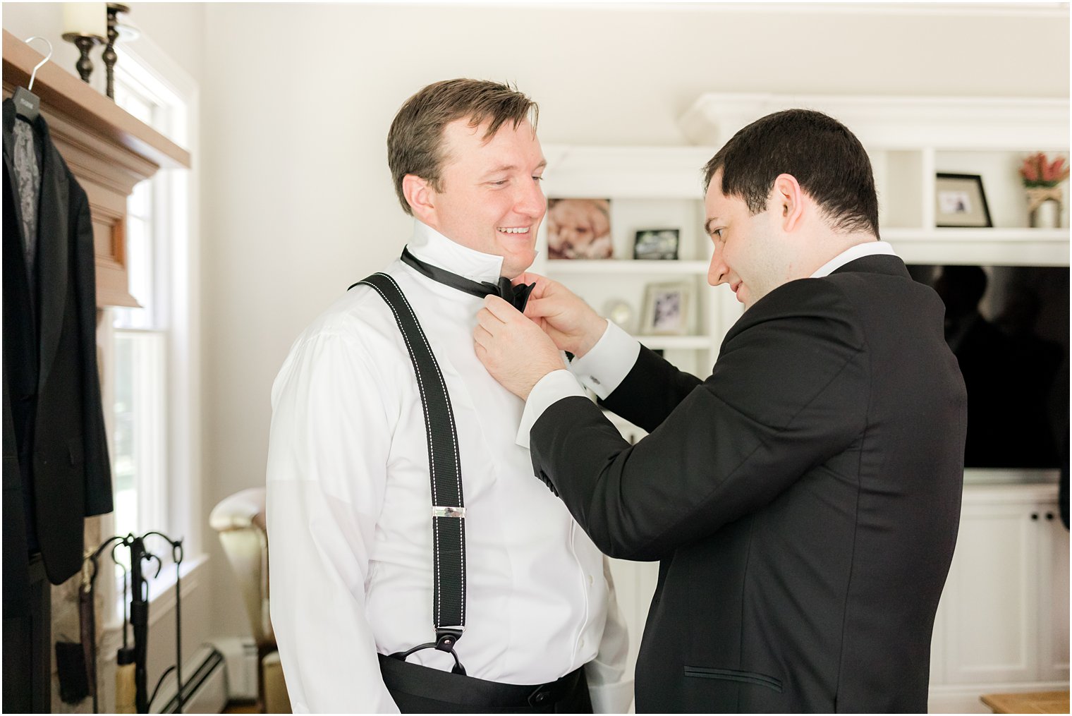 groomsman helps with groom with bowtie