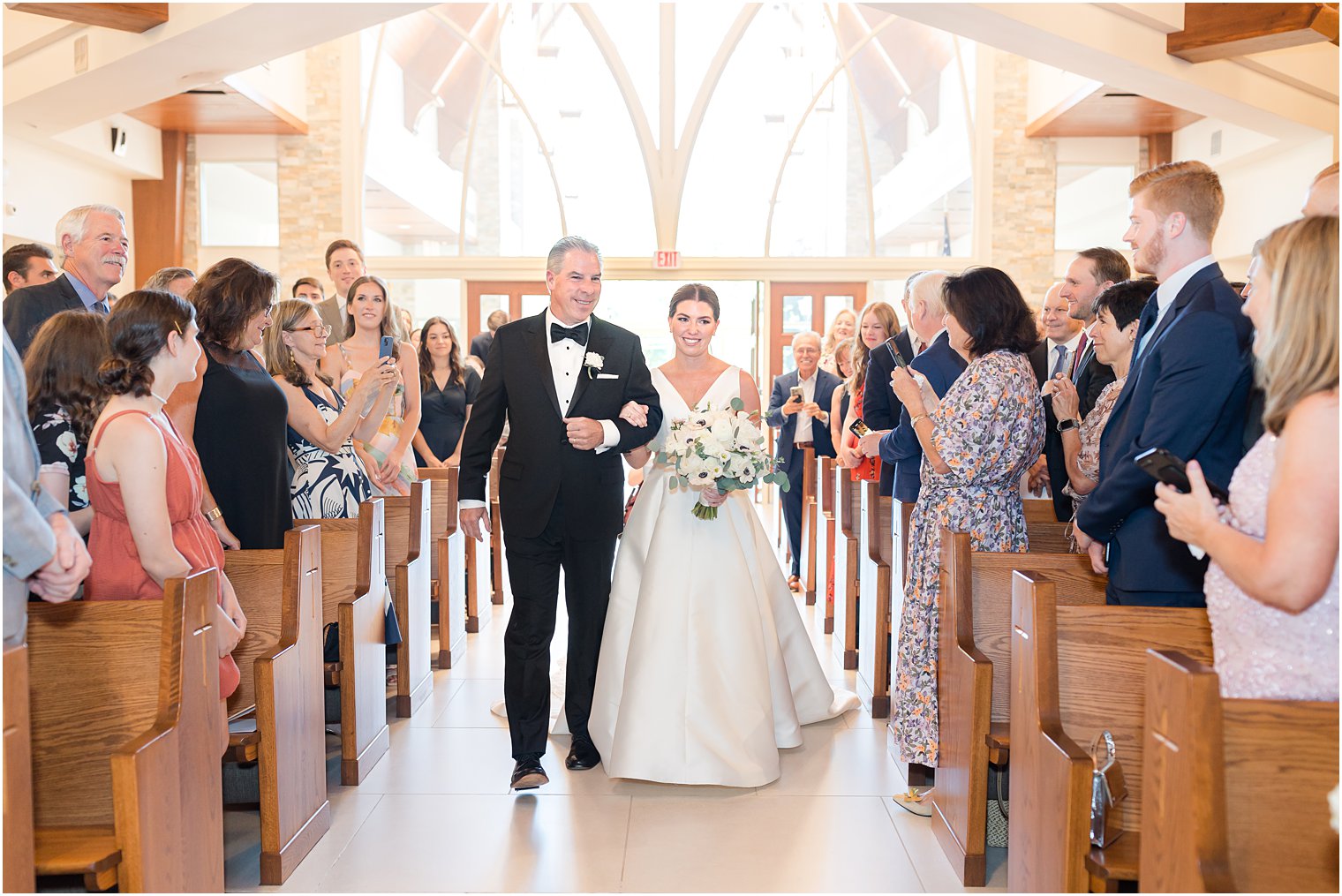 bride walks down aisle with father during traditional wedding ceremony at the Church of the Presentation