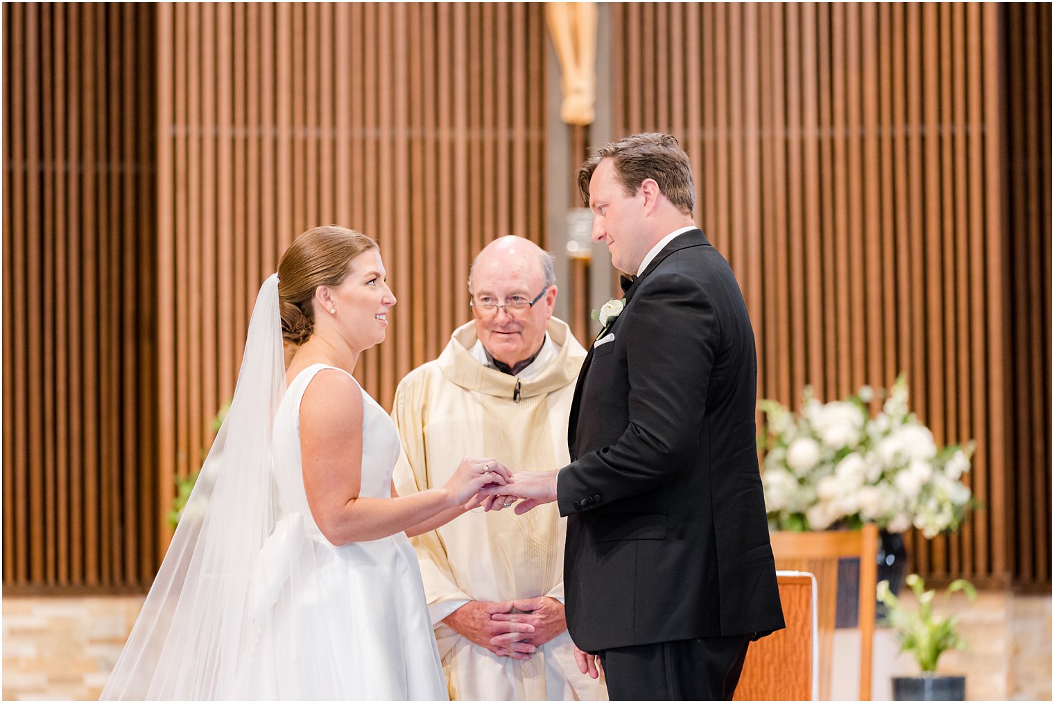 bride and groom exchange rings during traditional wedding ceremony at the Church of the Presentation