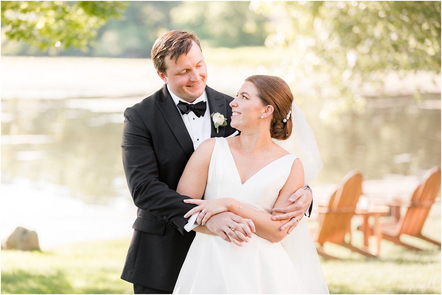 bride looks up at groom hugging her from behind 