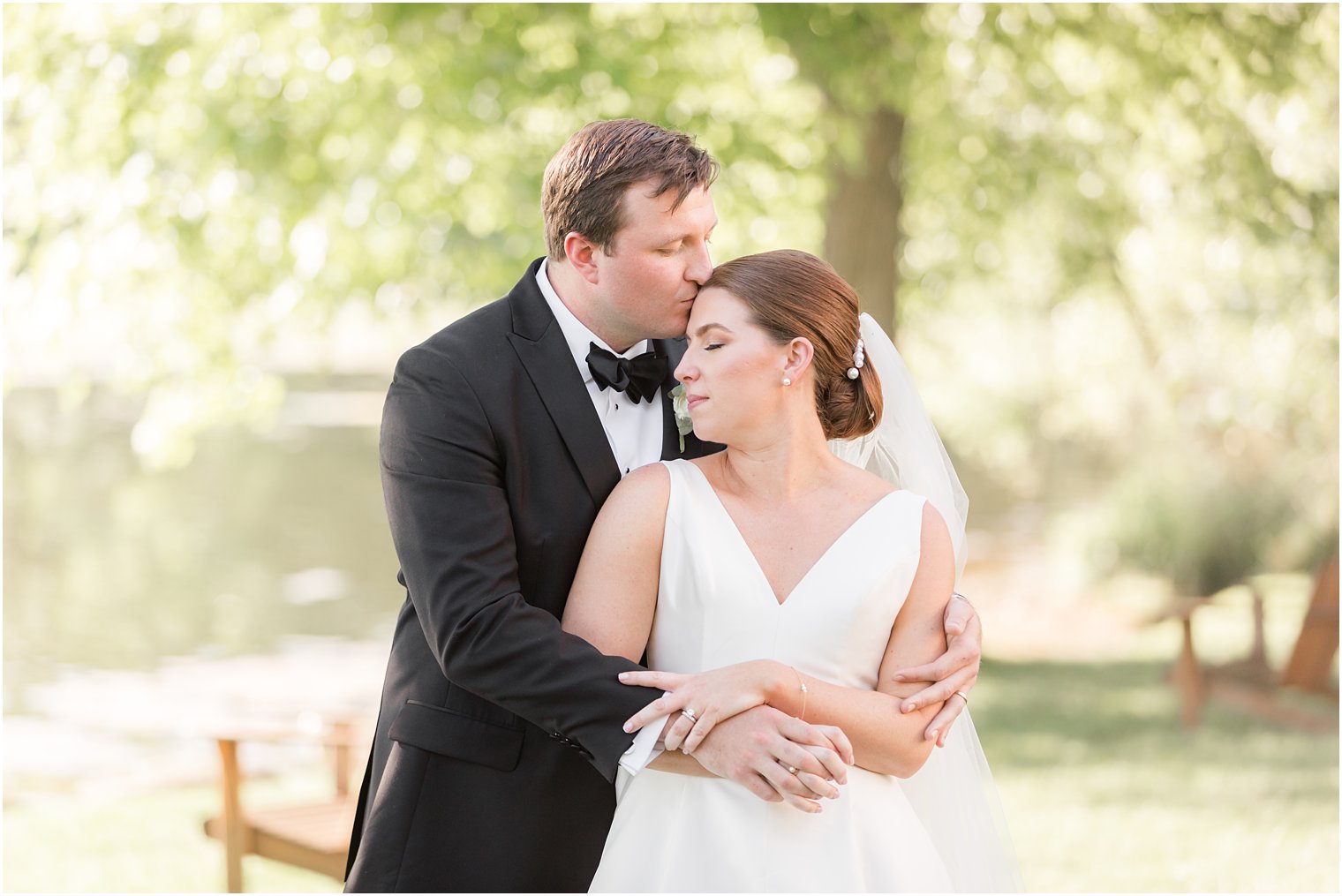 groom hugs bride kissing her forehead 