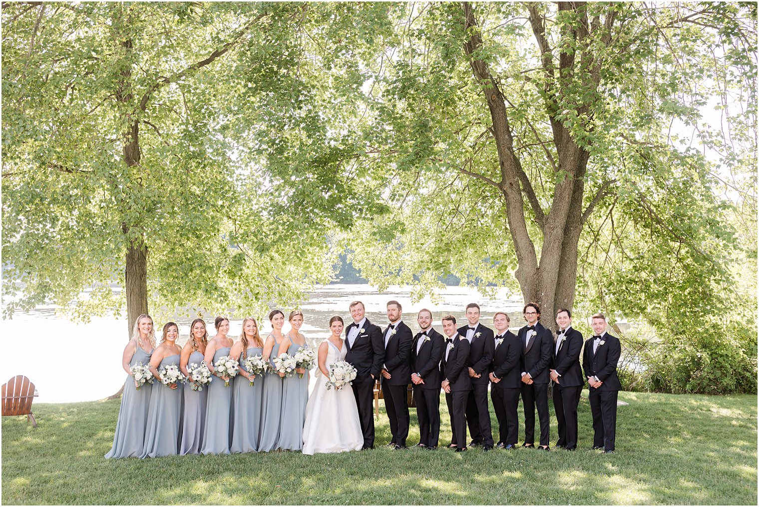 bride and groom stand with wedding party in blue and black at Indian Trail Club