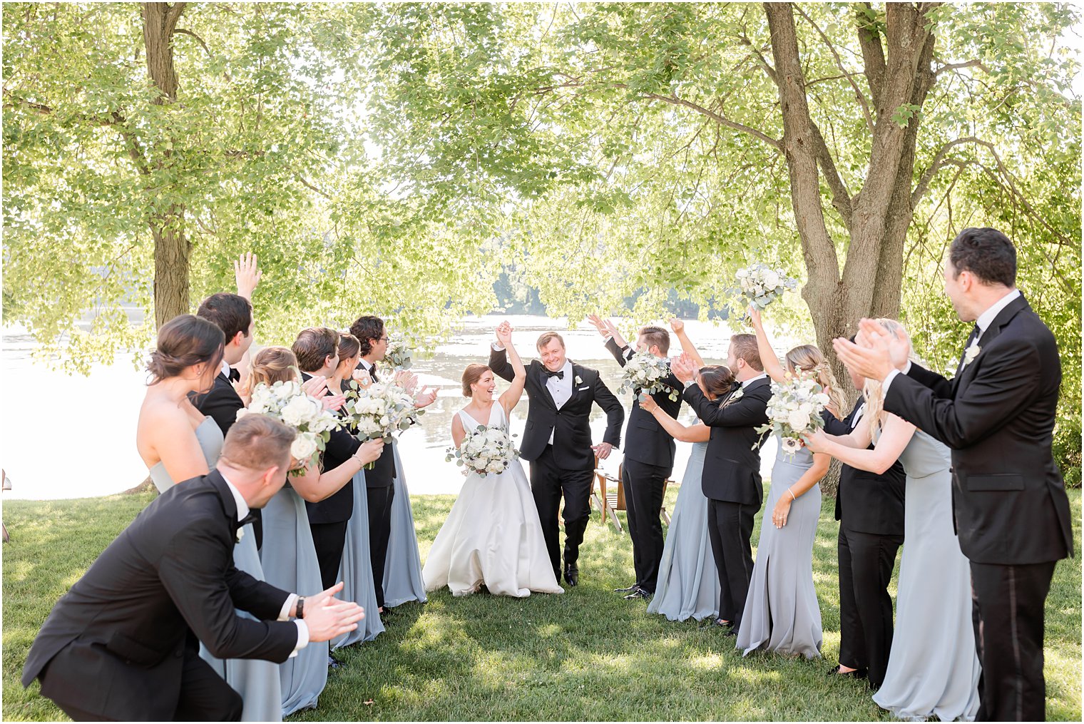 wedding party cheers as bride and groom run between them