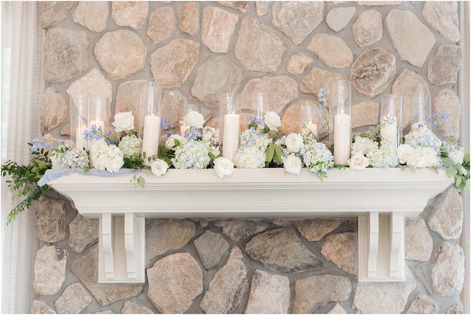 stone fireplace with candles and blue and white flowers at Indian Trail Club