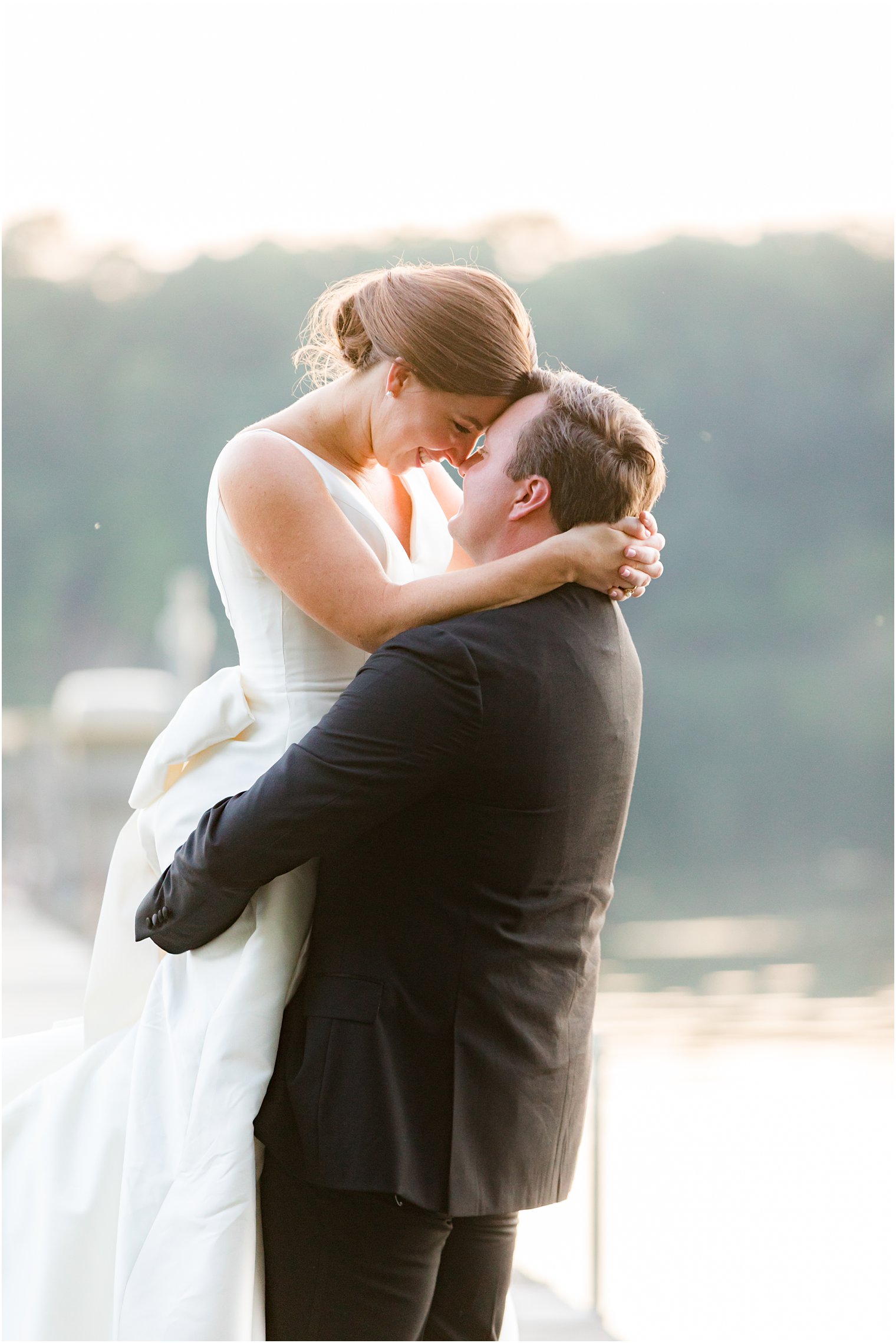 groom lifts up bride holding her to him at sunset 