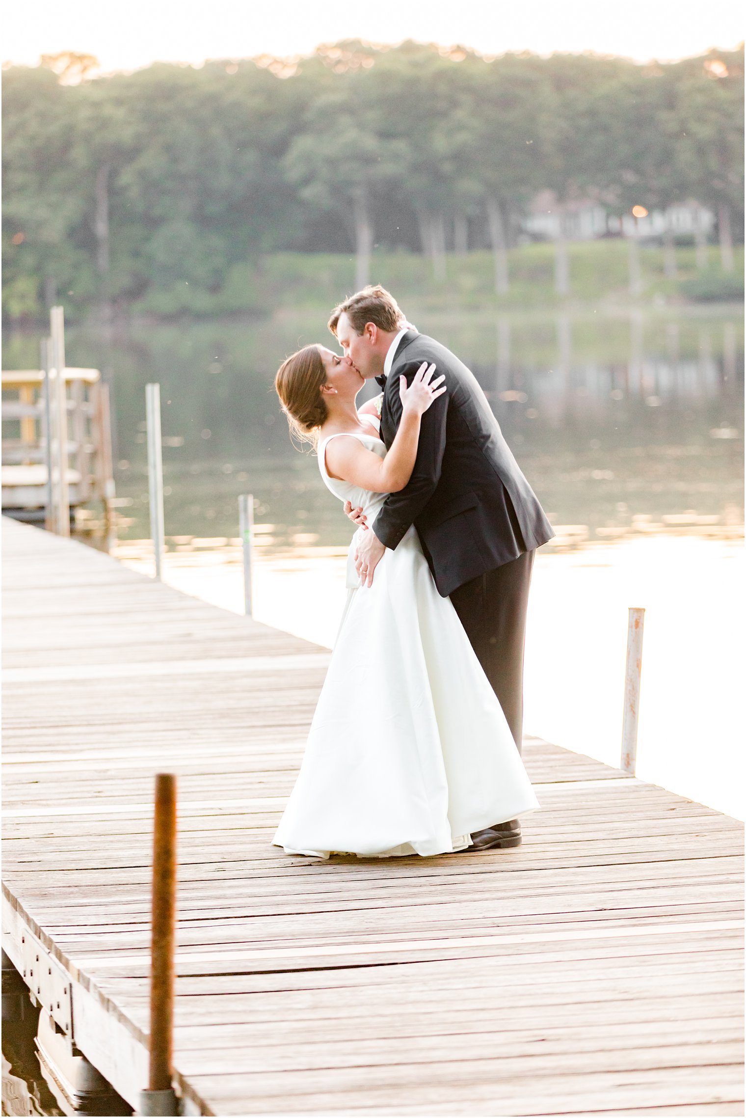 groom dips bride kissing her at Indian Trail Club on dock