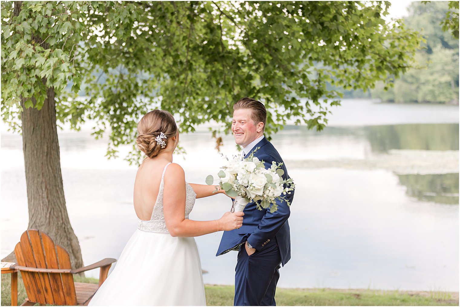 bride taps groom's shoulder by water at Indian Trail Club
