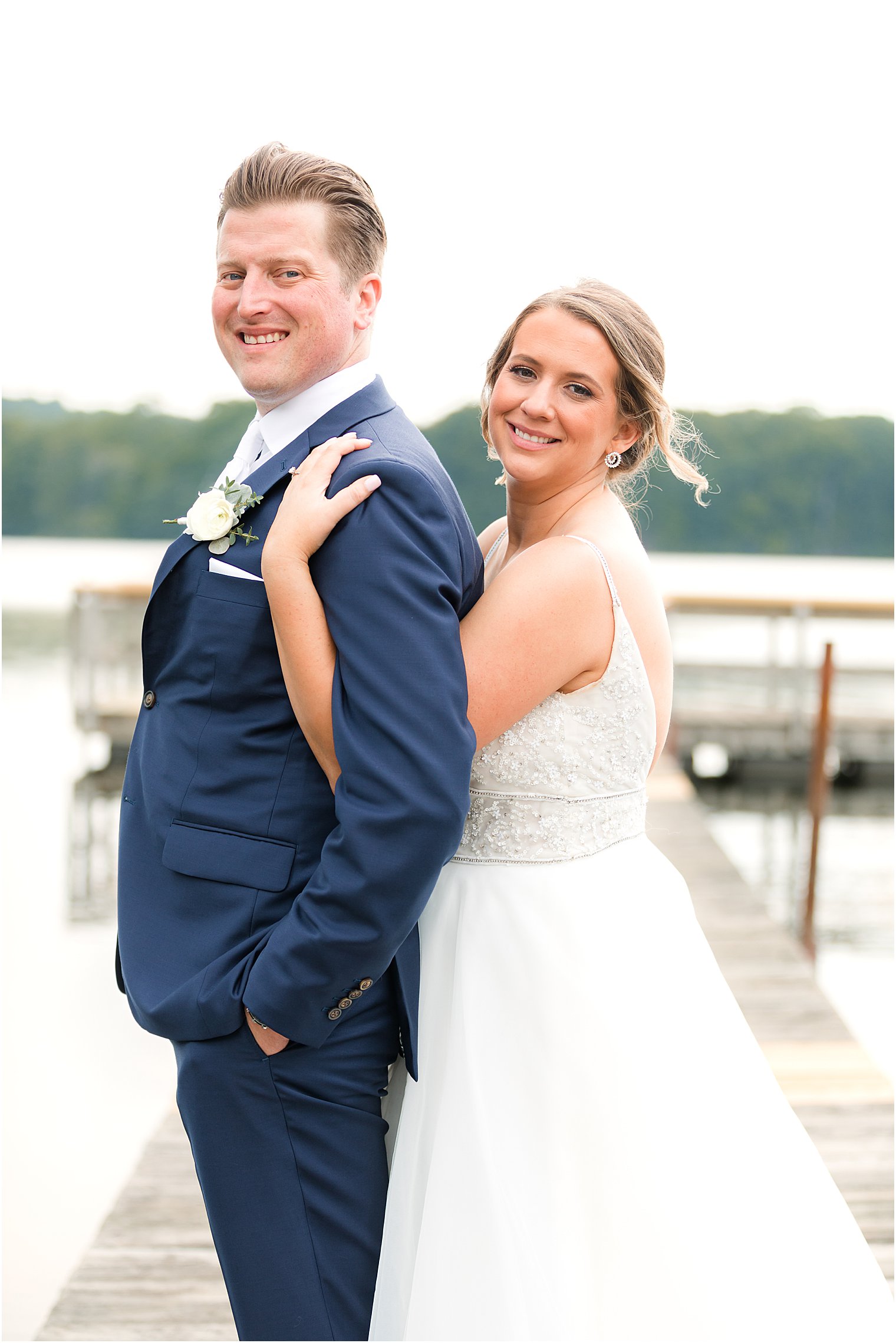 bride hugs groom from behind on dock at Indian Trail Club