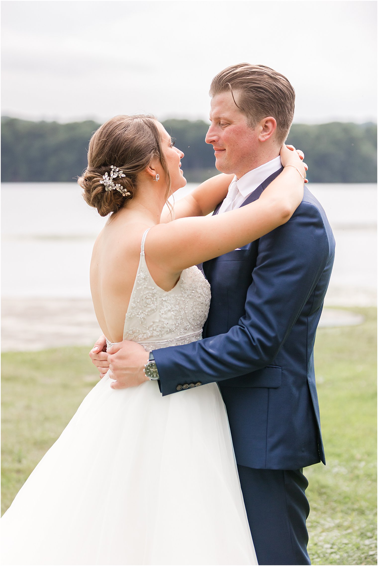 newlyweds hug during portraits along water at Indian Trail Club