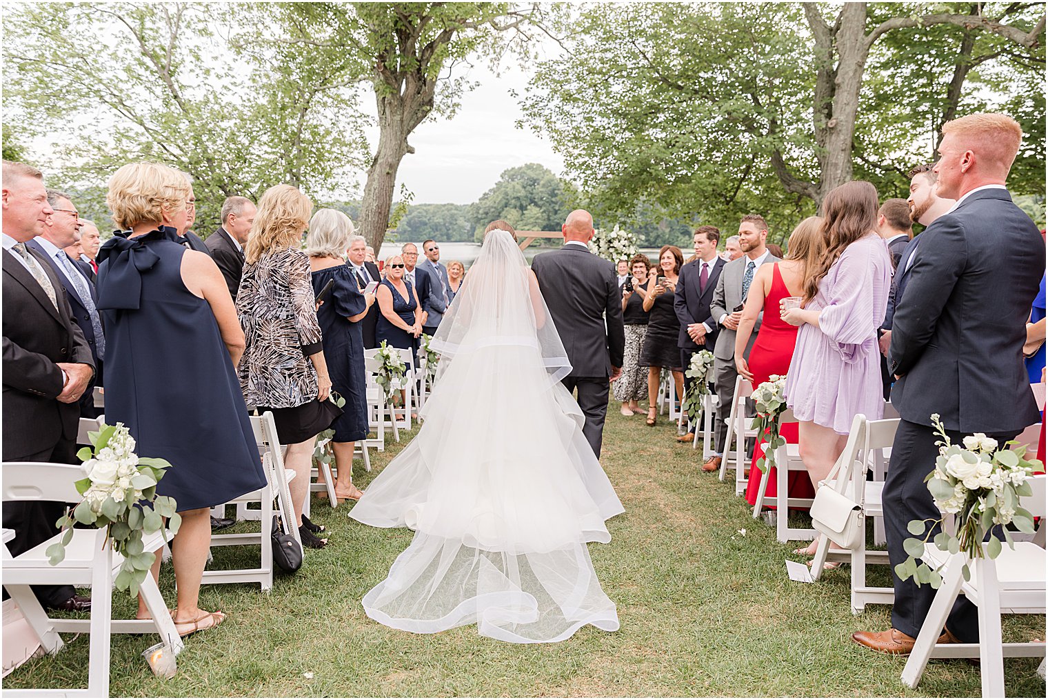 bride and father enter outdoor wedding ceremony by water at Indian Trail Club