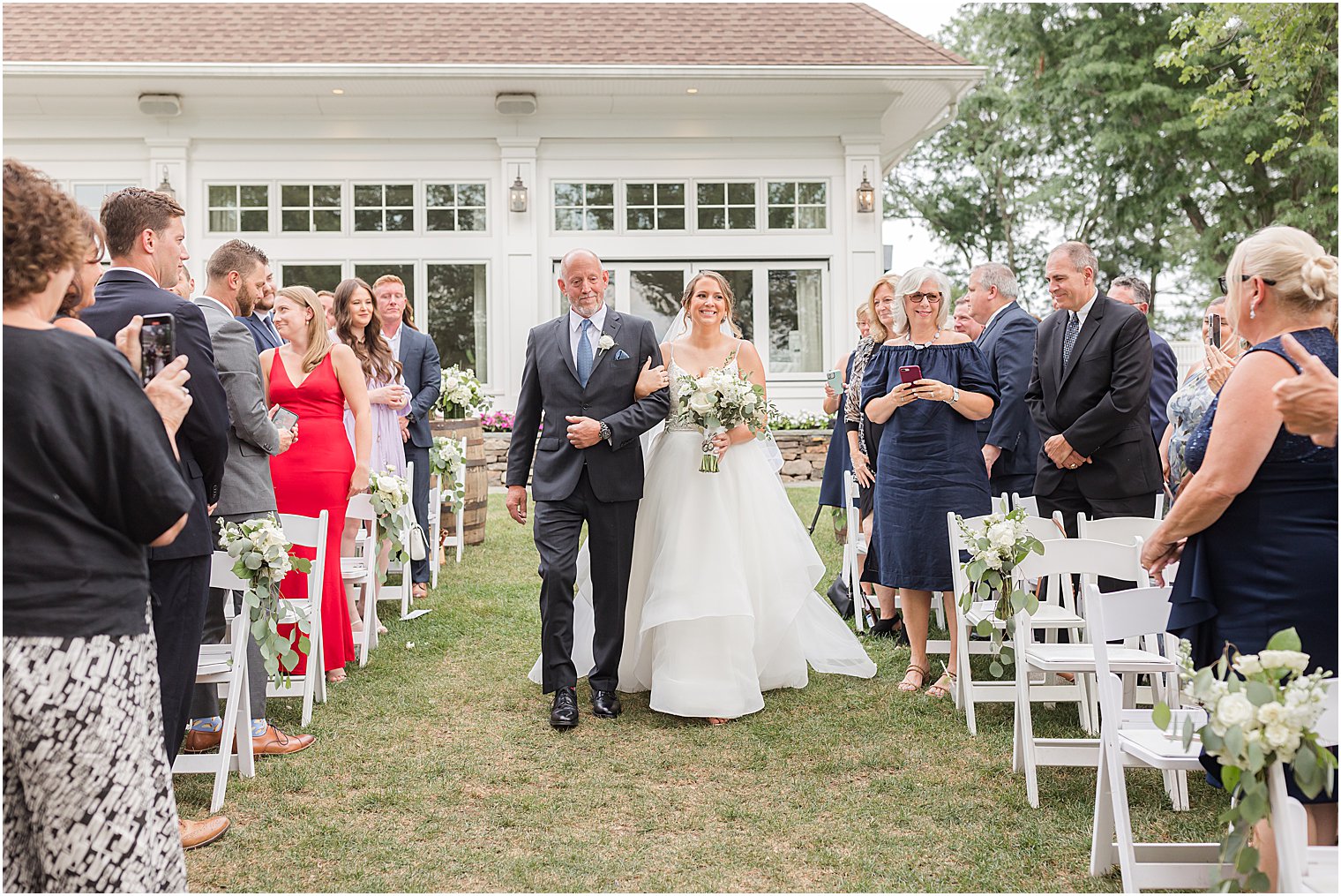 bride and dad walk down aisle for outdoor wedding ceremony by water at Indian Trail Club