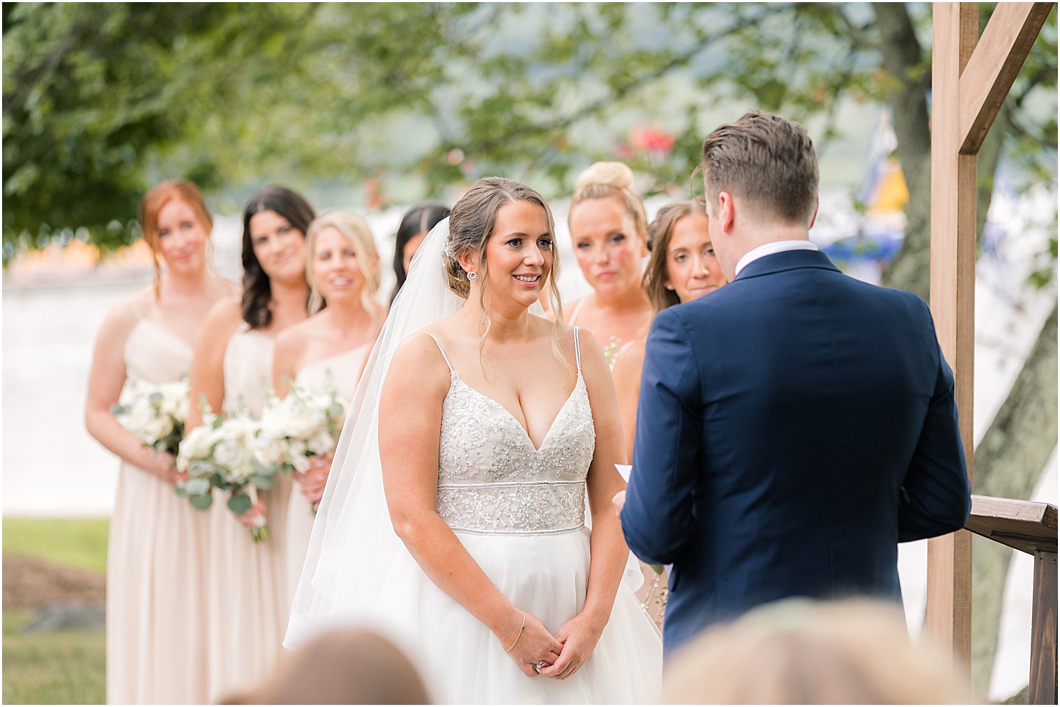 bride smiles at groom during outdoor wedding ceremony by water at Indian Trail Club