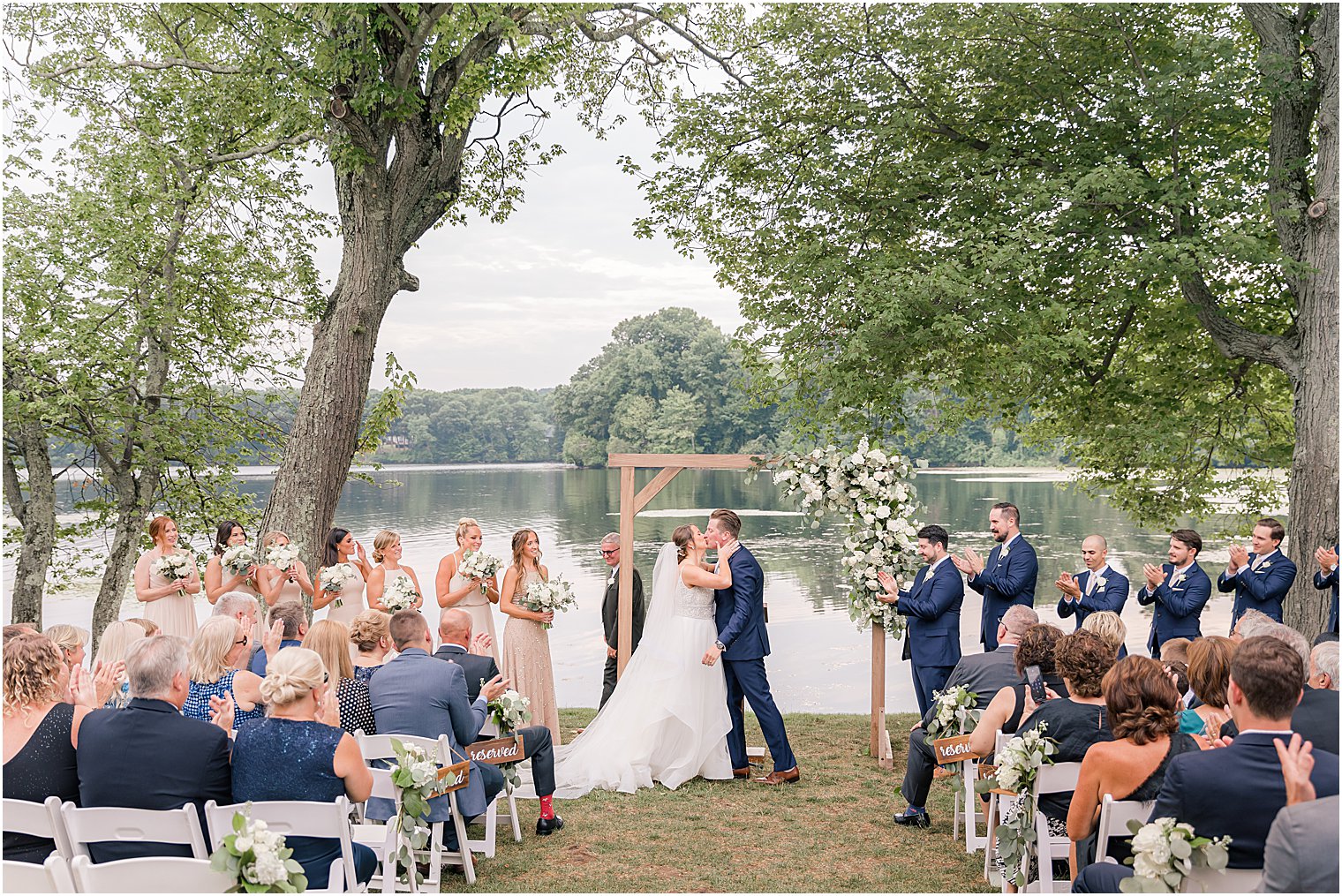 newlyweds kiss during outdoor wedding ceremony by water at Indian Trail Club