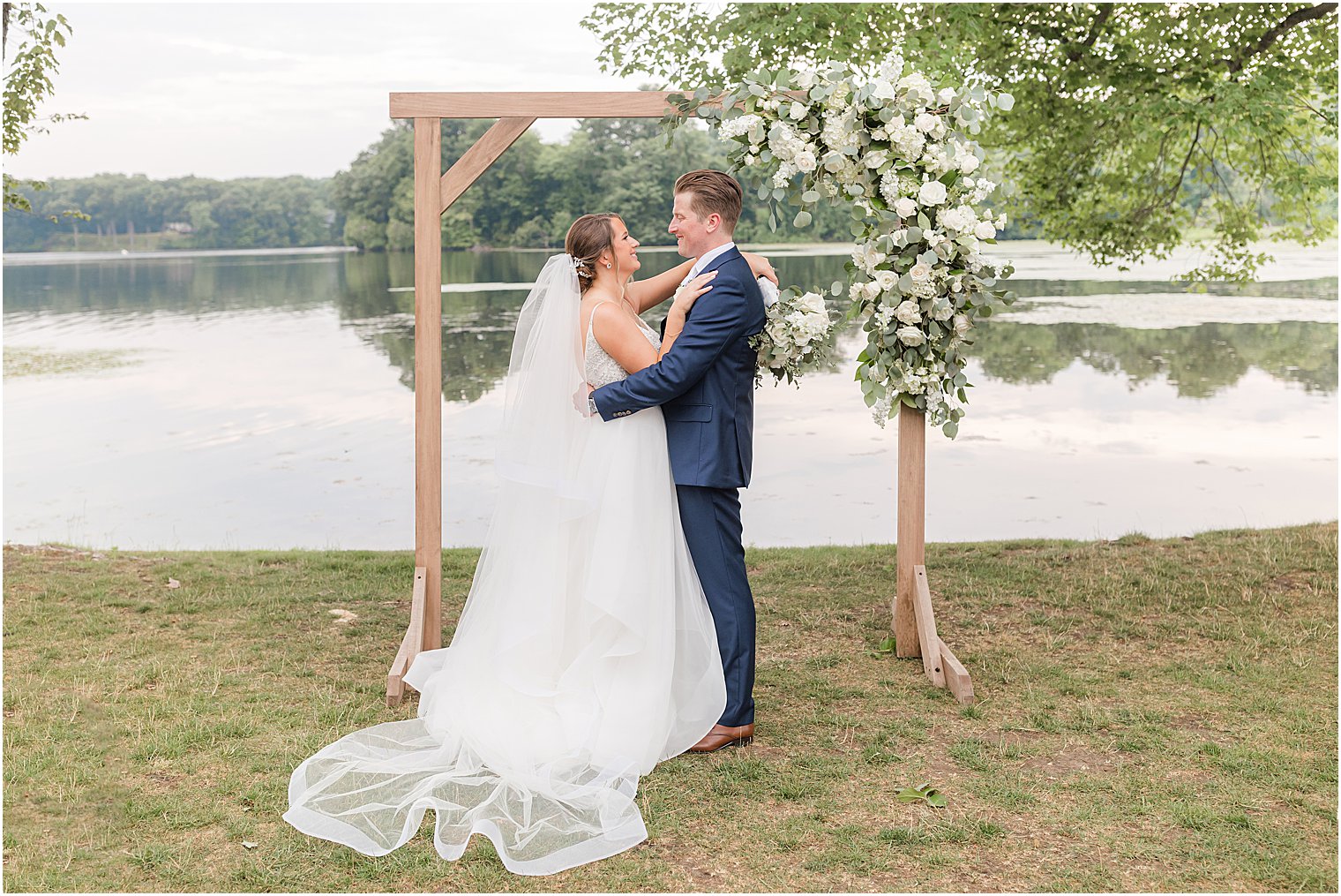bride and groom hug by wooden arbor at Indian Trail Club