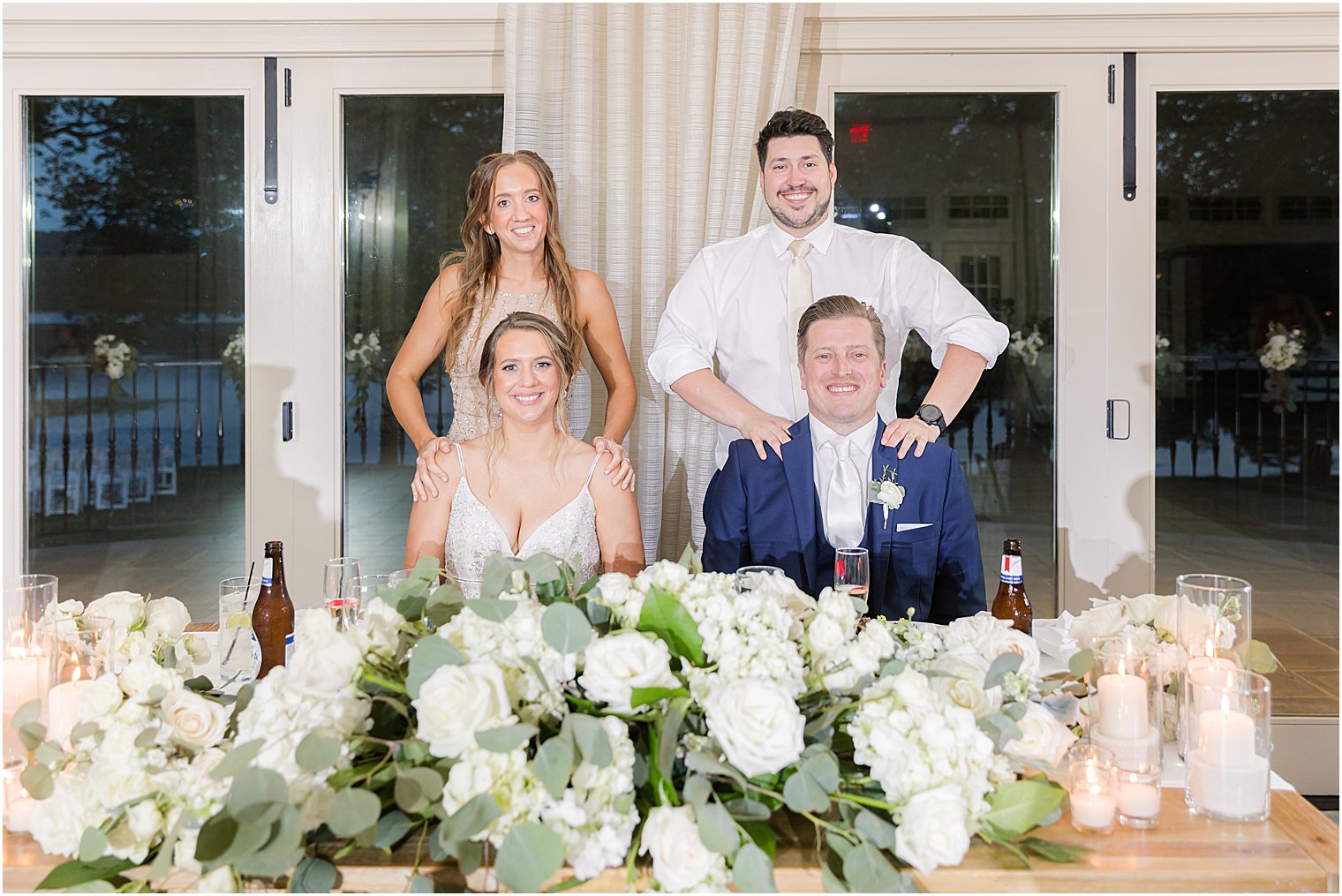 bride and groom sit at sweetheart table with maid of honor and best man