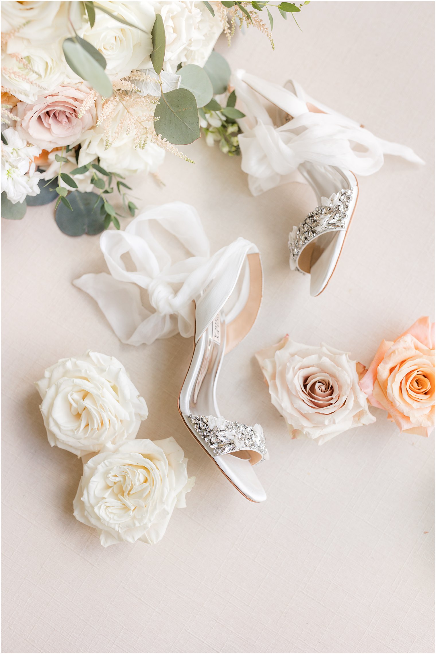 bride's shoes lay with pink and peach roses