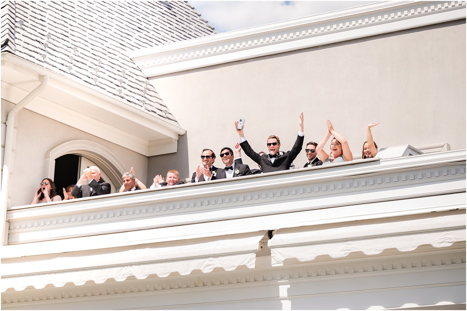 bridal party cheers on balcony during first look