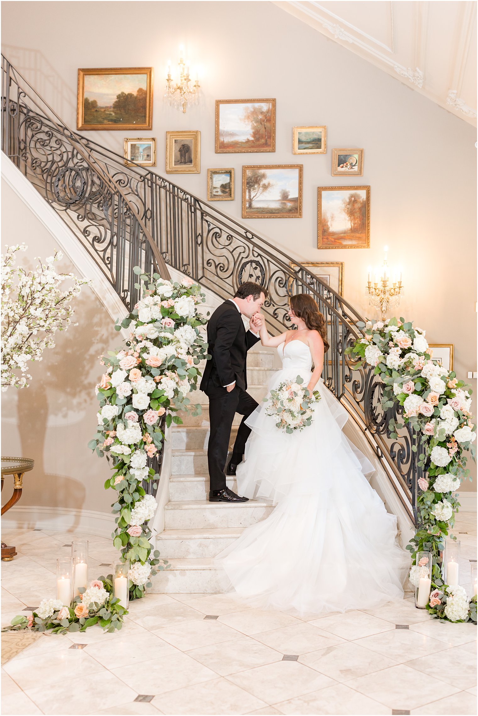 groom kisses bride's hand on staircase in Park Chateau Estate