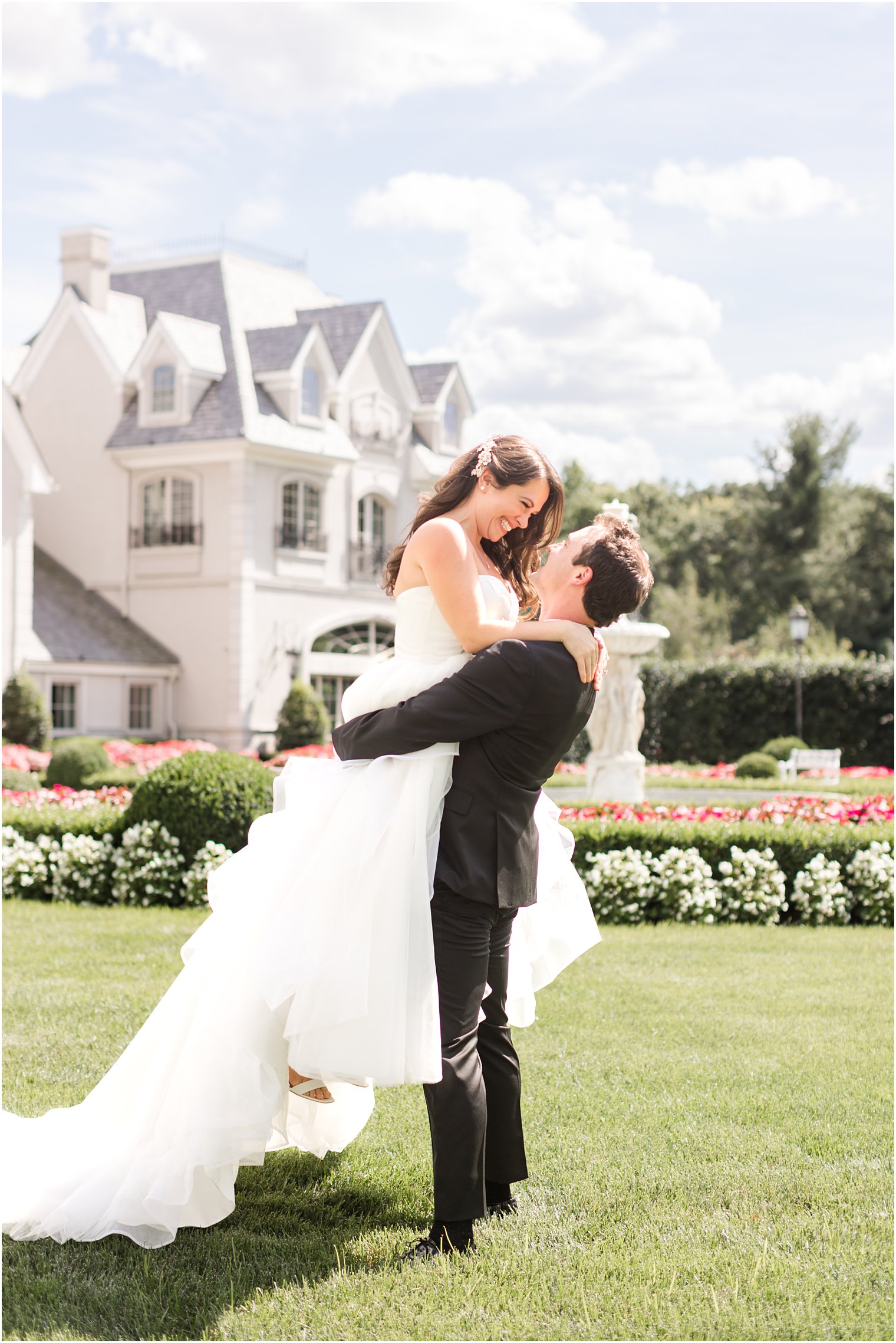 groom lifts bride up on lawn at Park Chateau Estate