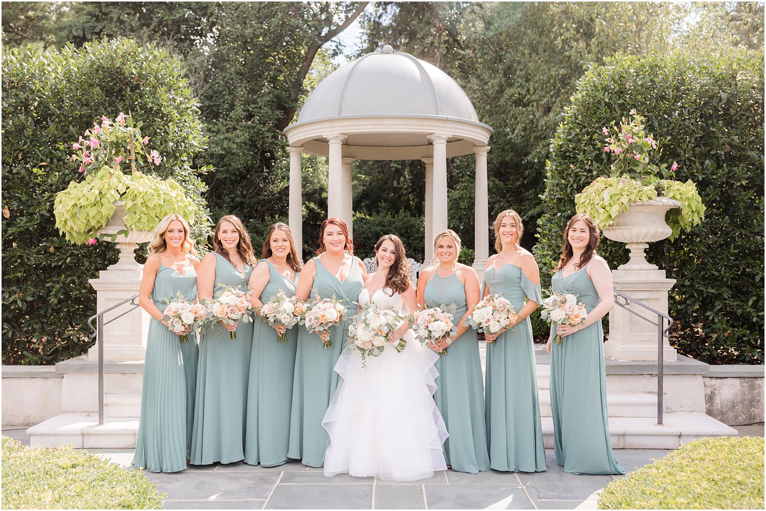 bride stands with bridesmaids in light green gowns