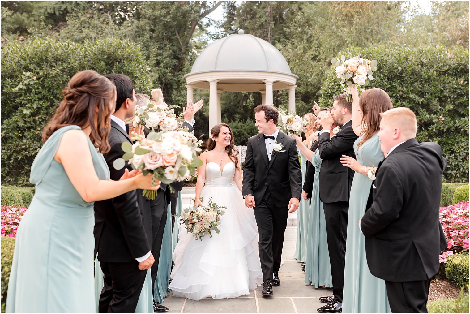 bride and groom hold hands walking between wedding party cheering