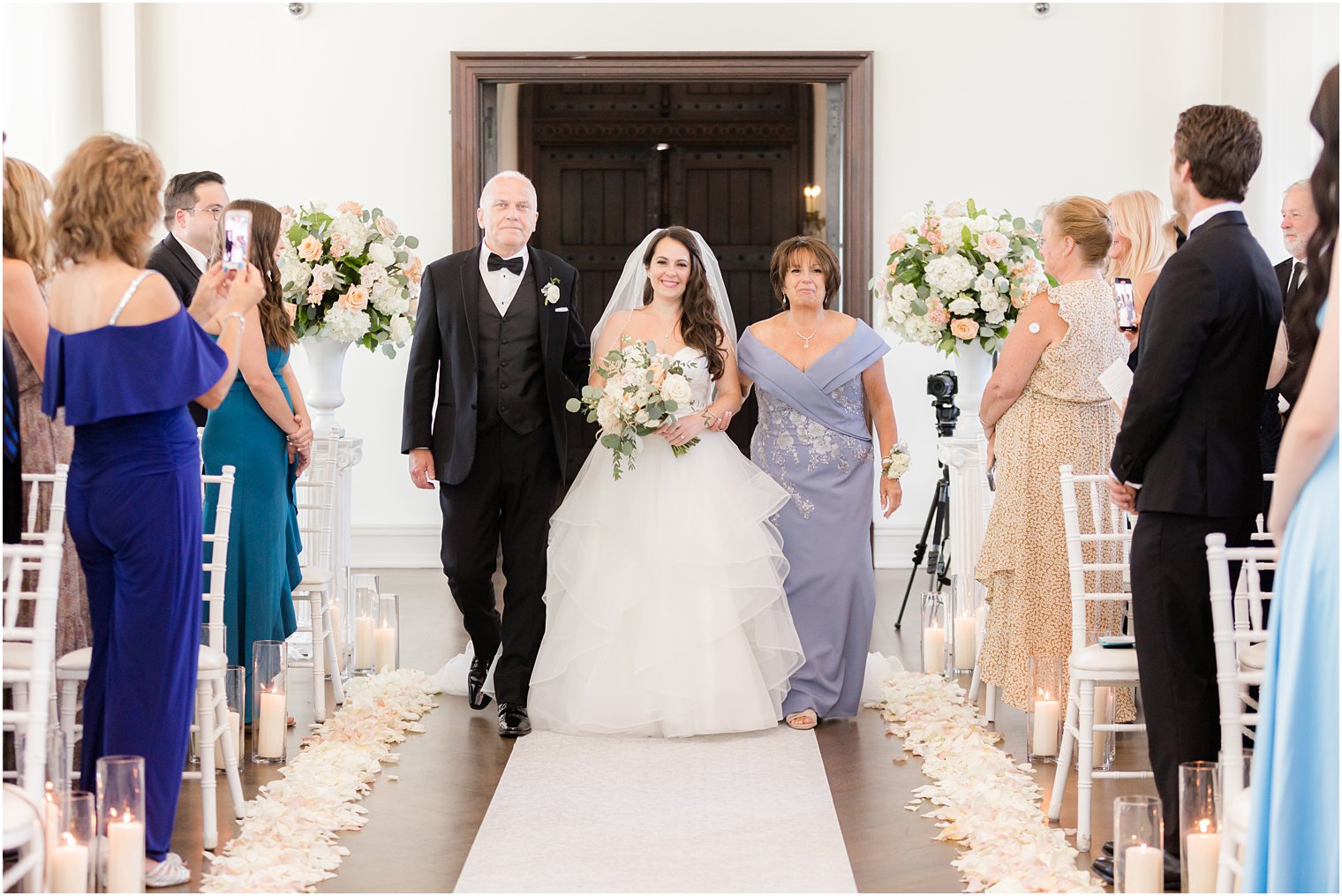 bride walks down aisle with parents during Park Chateau Estate wedding ceremony