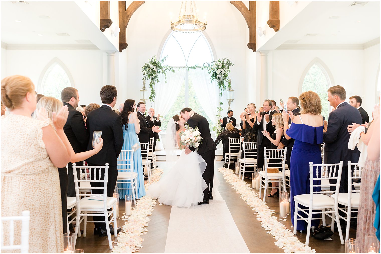 newlyweds kiss walking up aisle at Park Chateau Estate