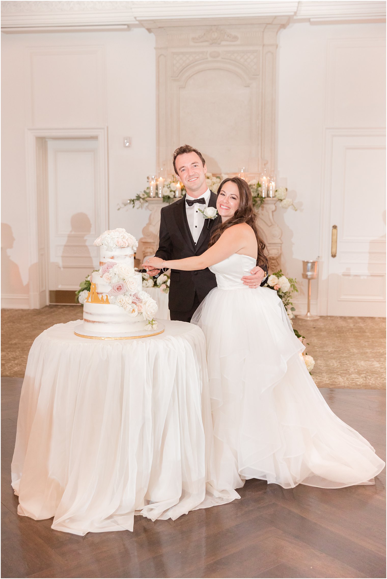 newlyweds hug by wedding cake at Park Chateau Estate