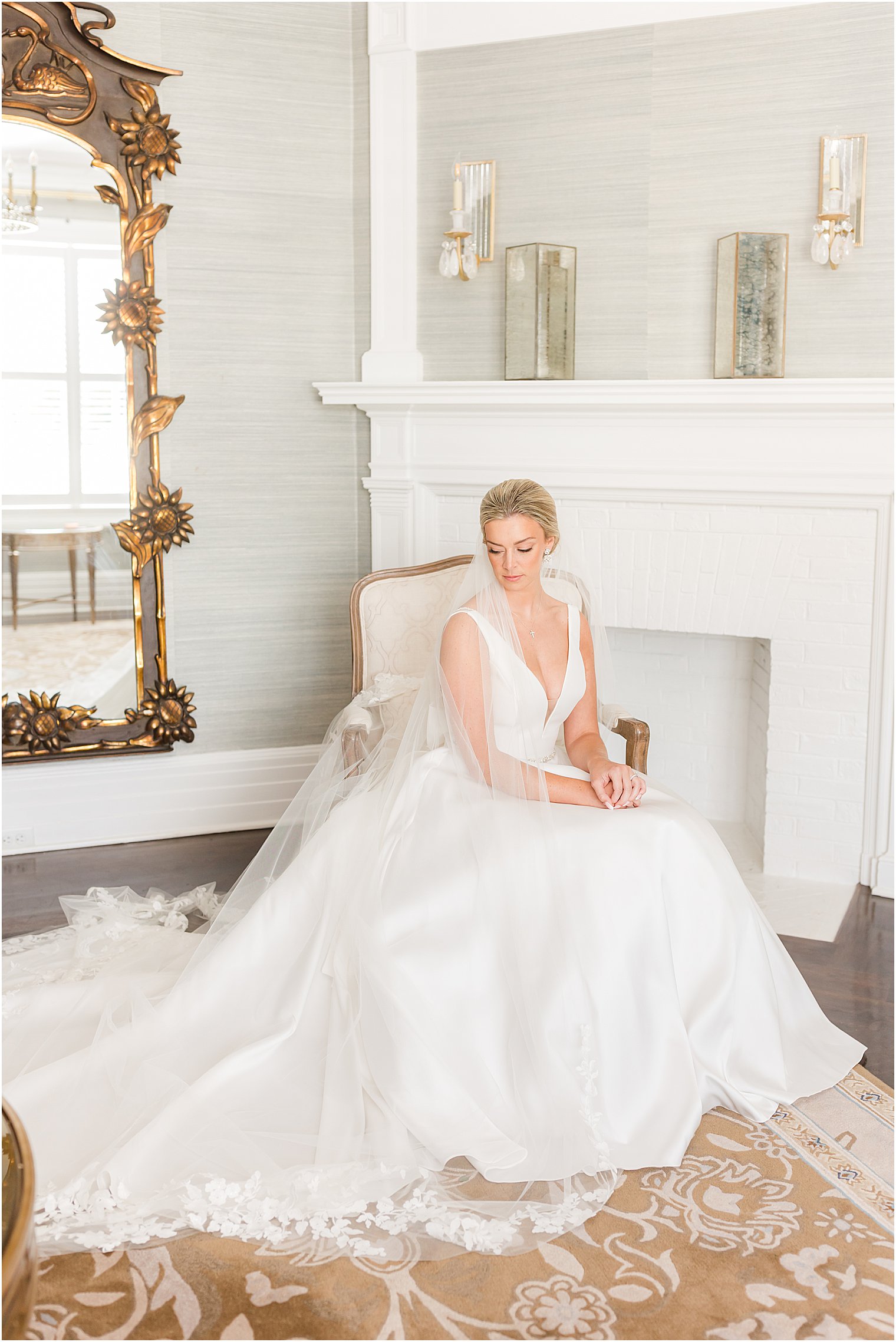 bride sits in chair by fireplace in bridal suite at Shadowbrook at Shrewsbury