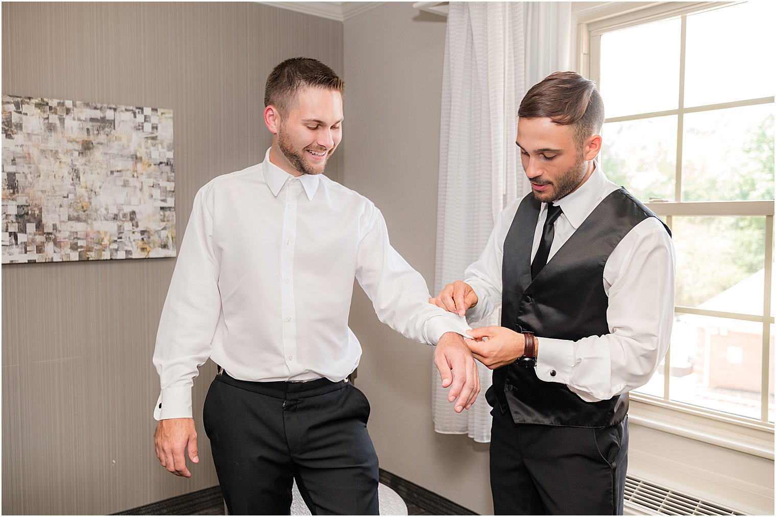 groomsman helps groom with cufflinks