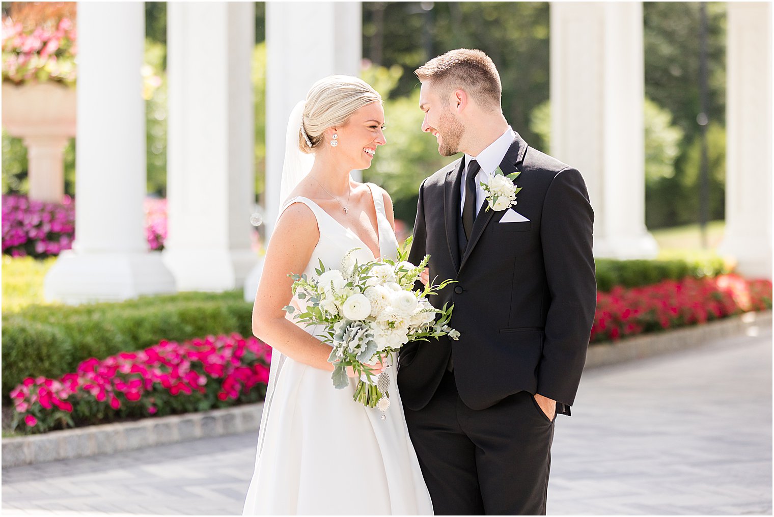 groom smiles at bride holding bouquet f white flowers
