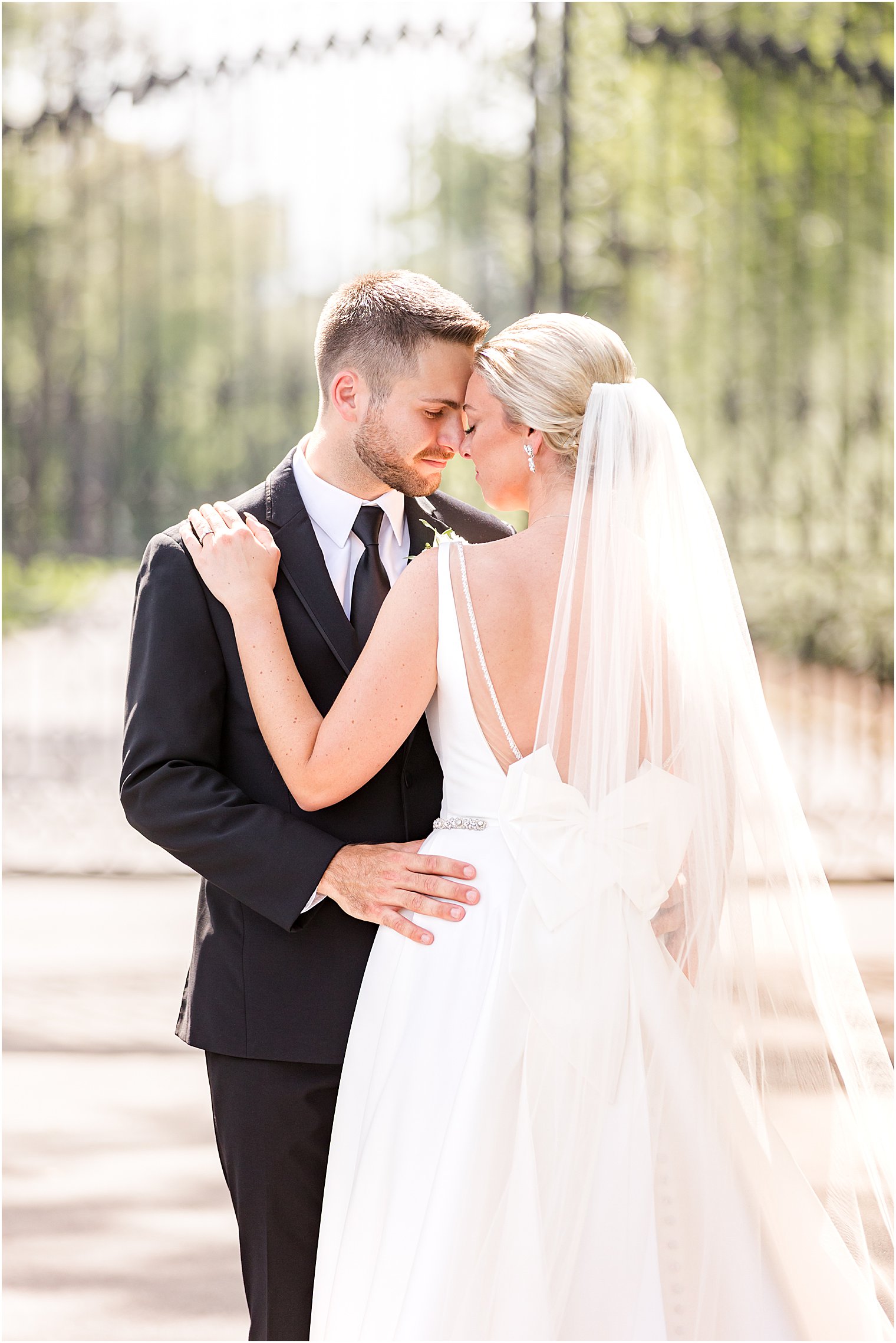 groom hugs bride to him showing off back of wedding gown