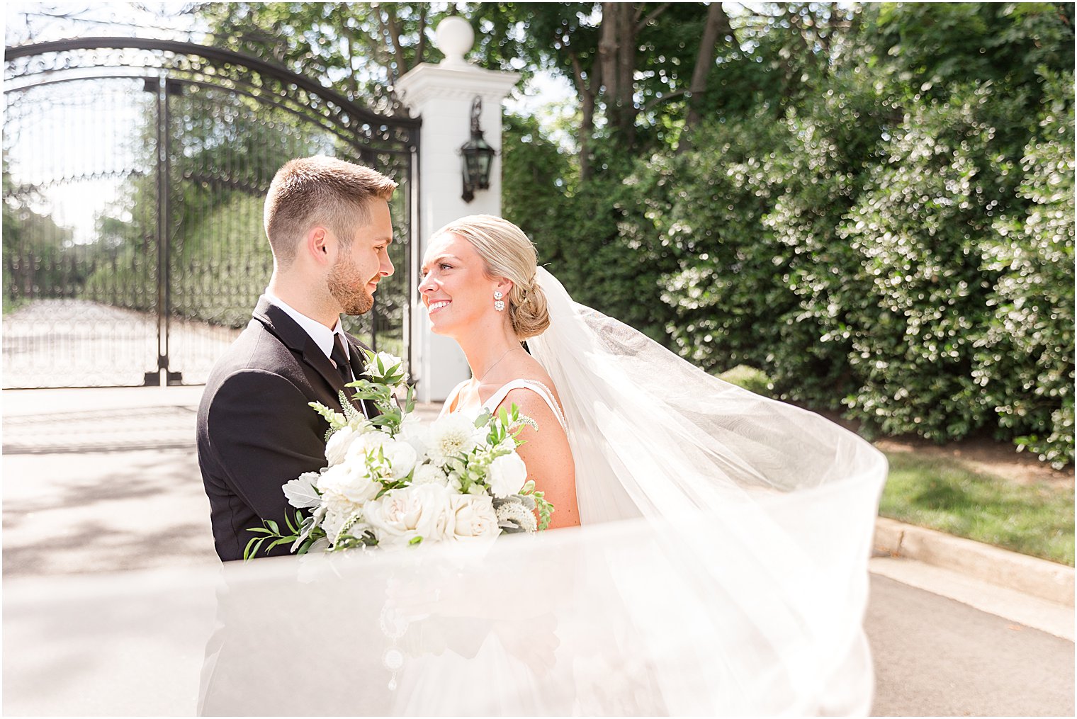 bride smiles up at groom with veil floating around them