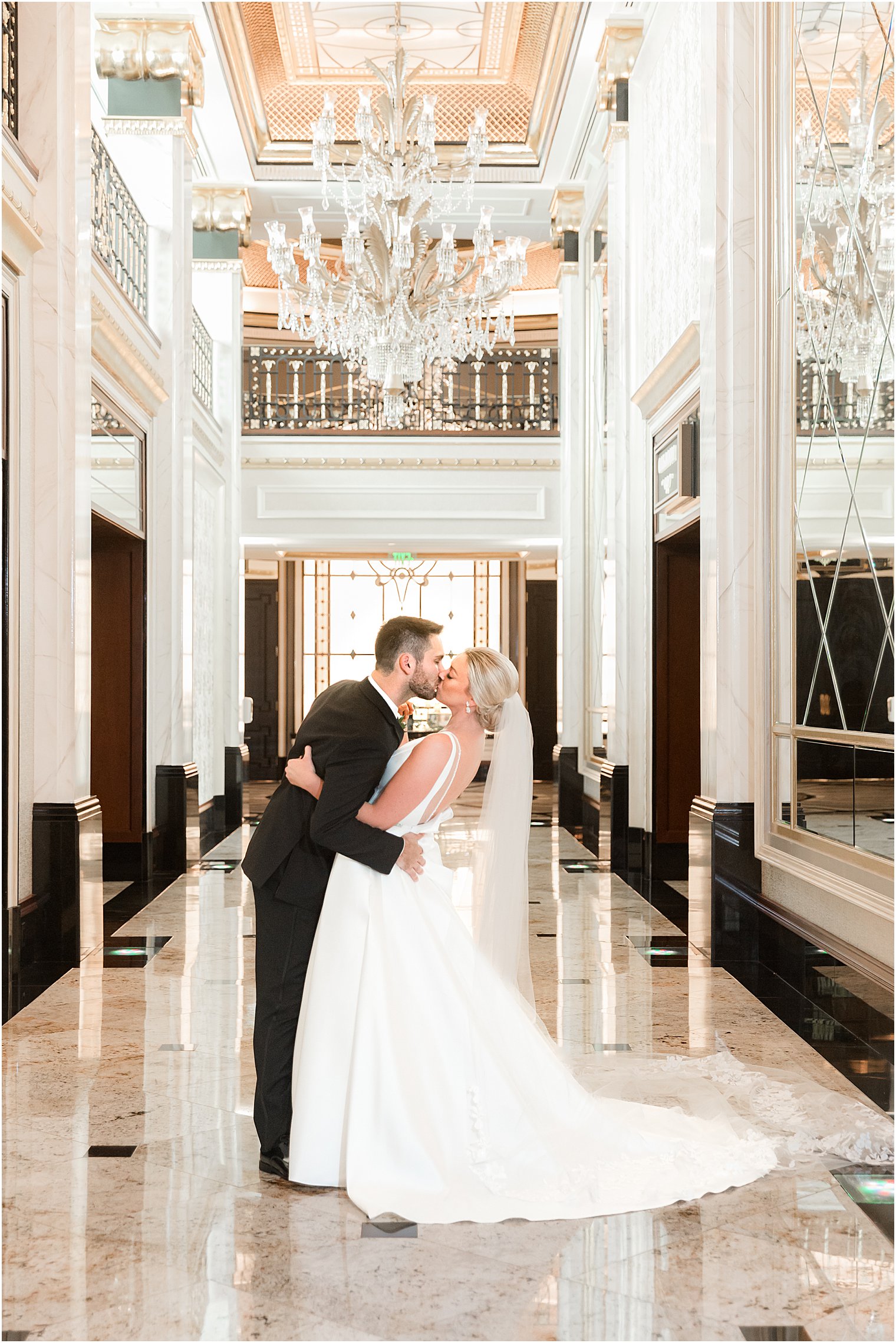 newlyweds kiss inside Shadowbrook at Shrewsbury under chandelier 