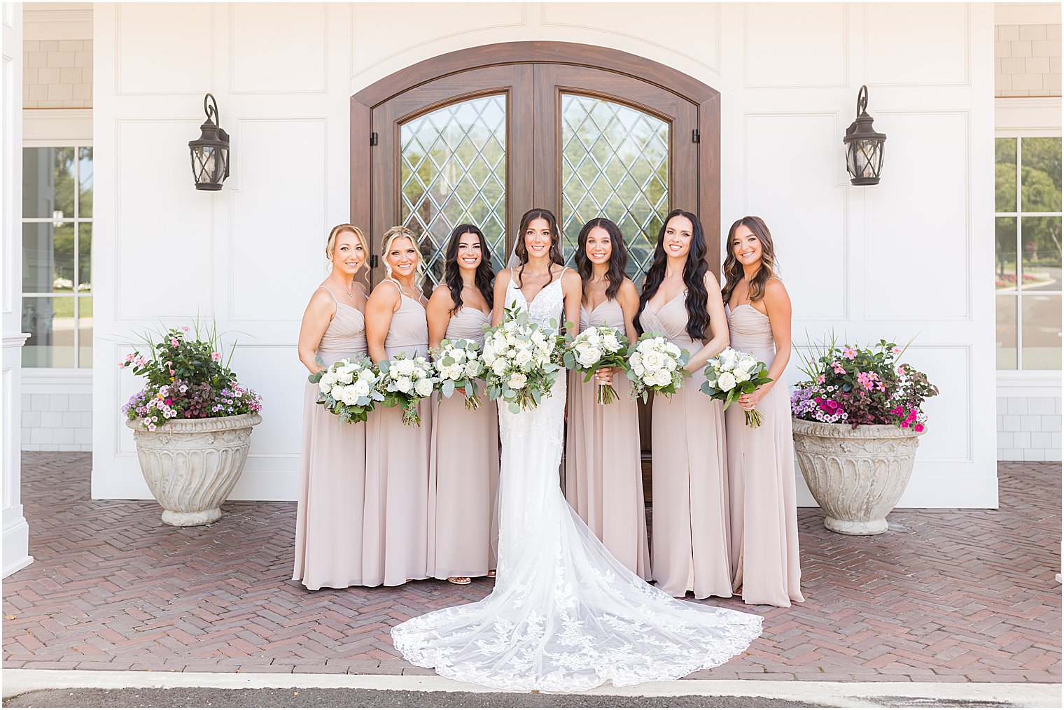 bride poses with bridesmaids outside wooden door at The Mill Lakeside Manor
